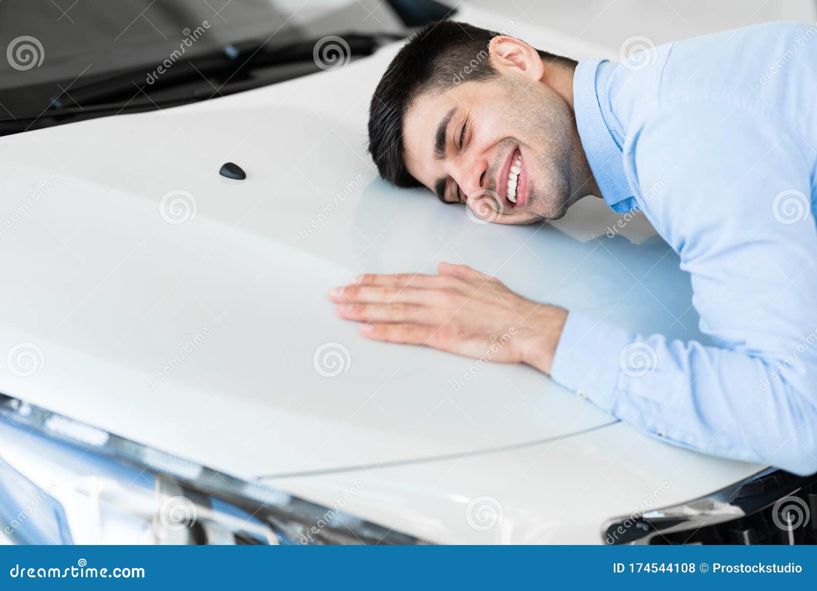 happy man hugging new car in auto dealership