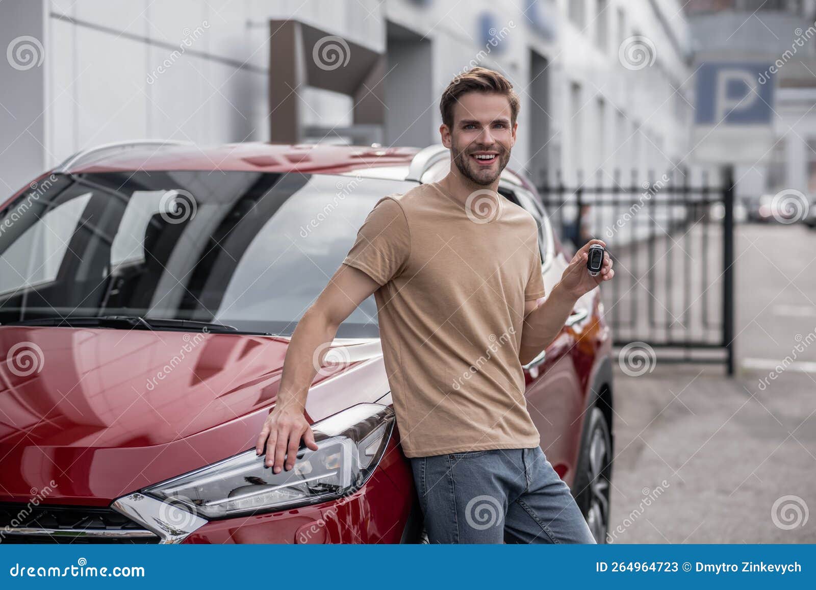 smiling contented man standing near the new car with keys