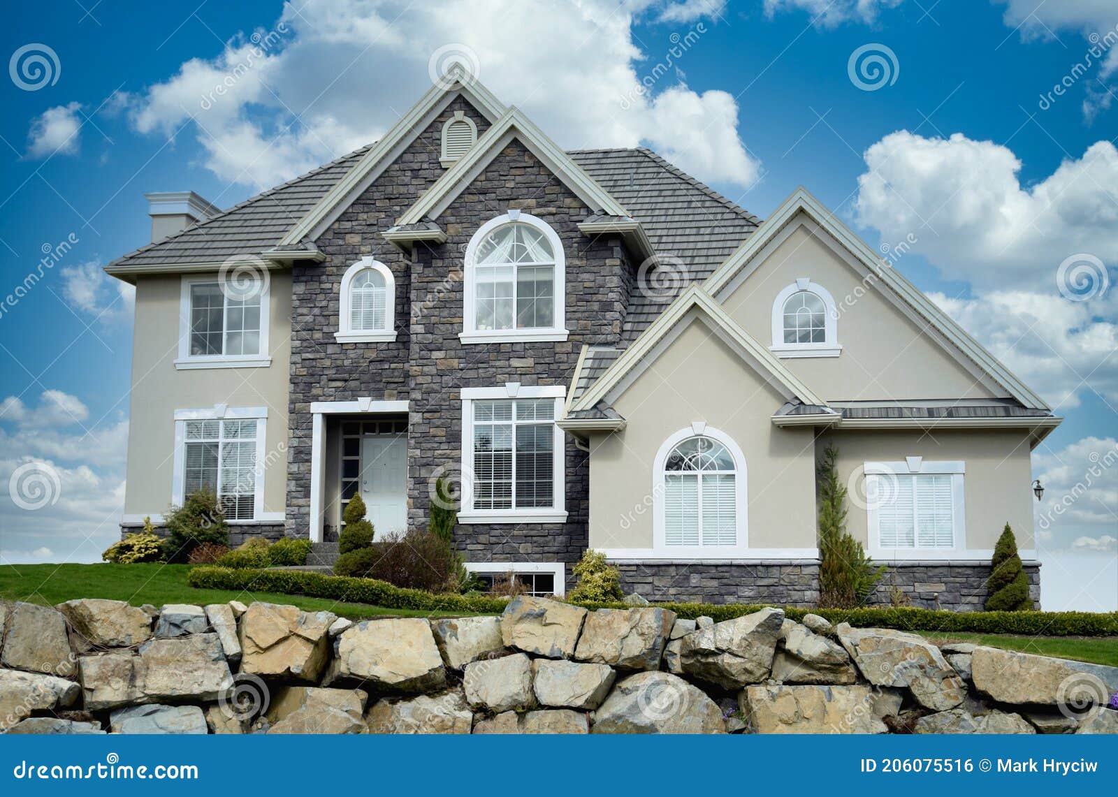 new home house custom cream rockwork exterior dramatic cloudy sky background