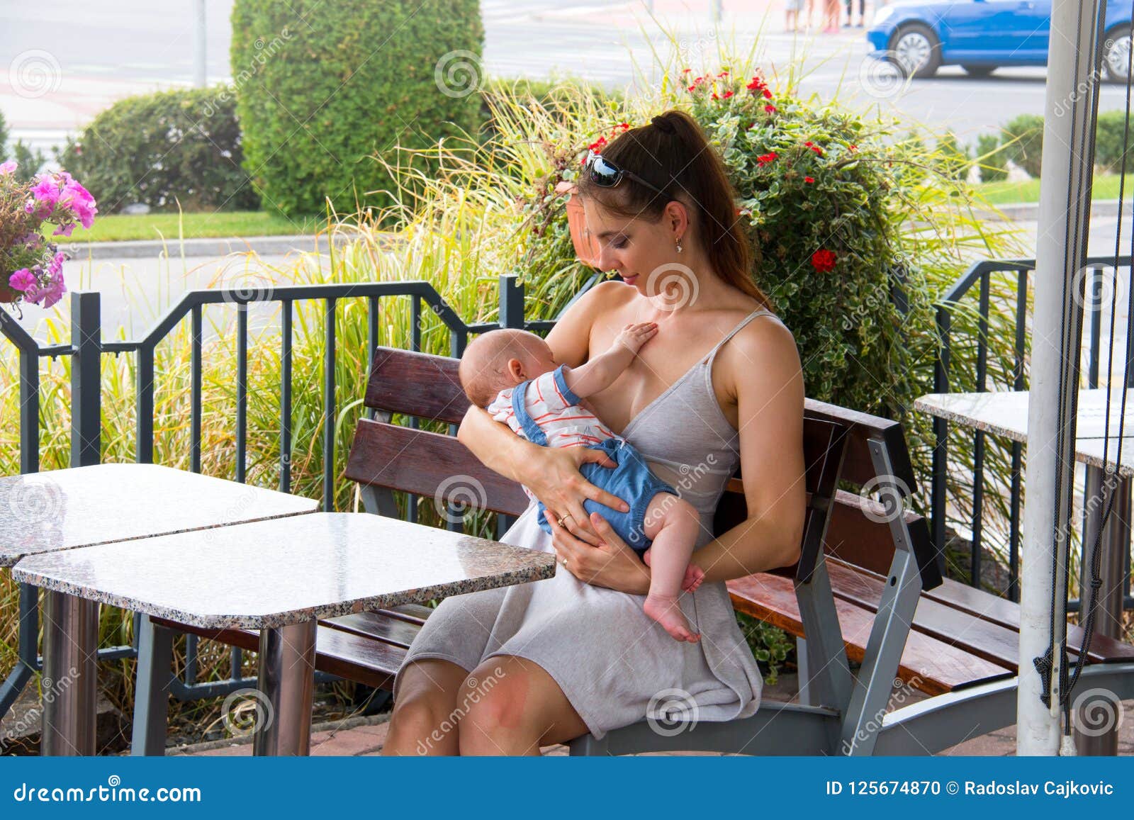 Young Mother Breastfeeding Baby Boy Outside During Beautiful Su