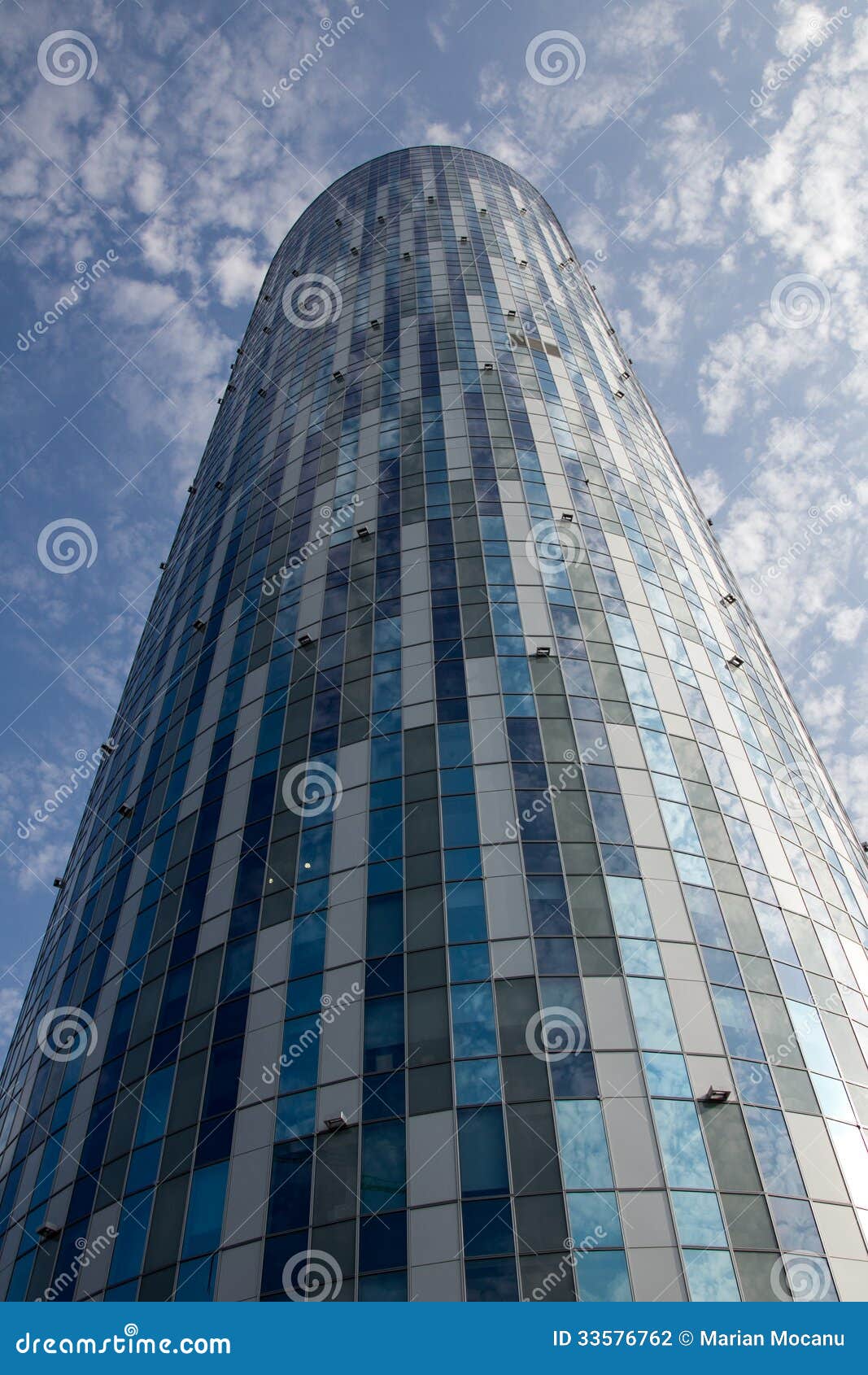 A tower of a new office building with blue sky and clouds