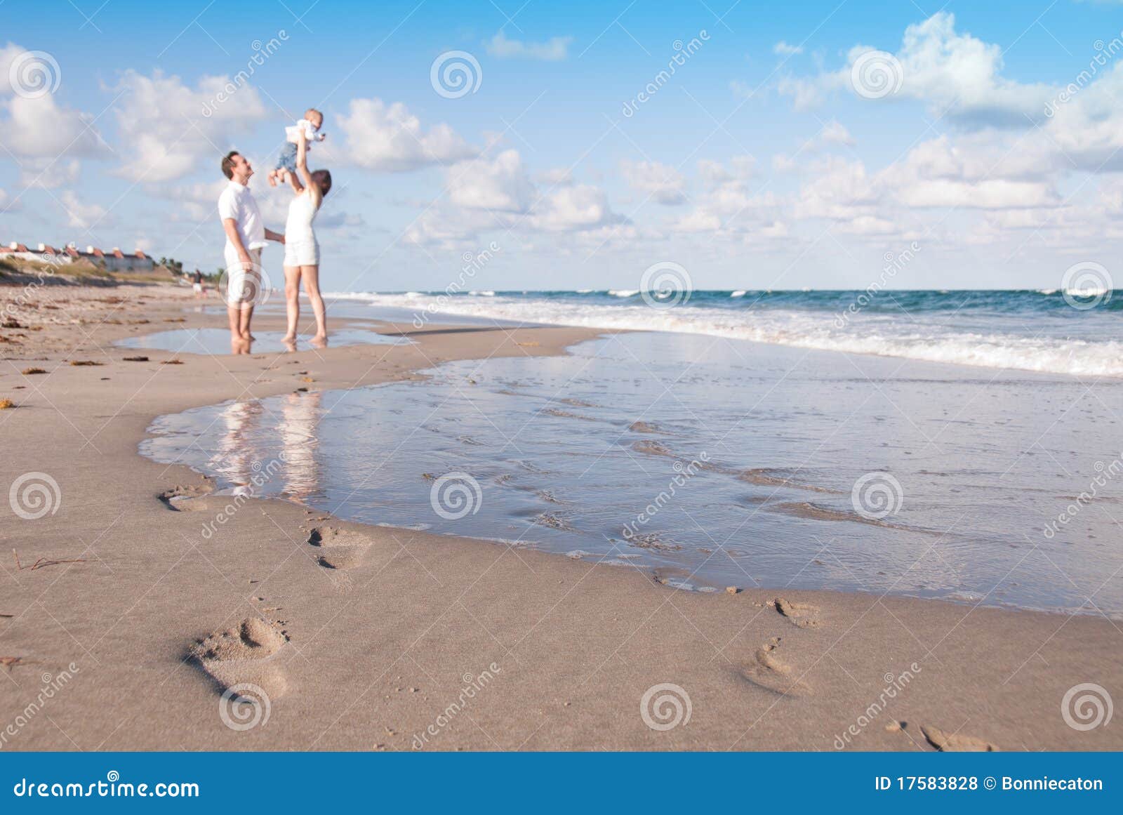 new parents play with baby on the beach