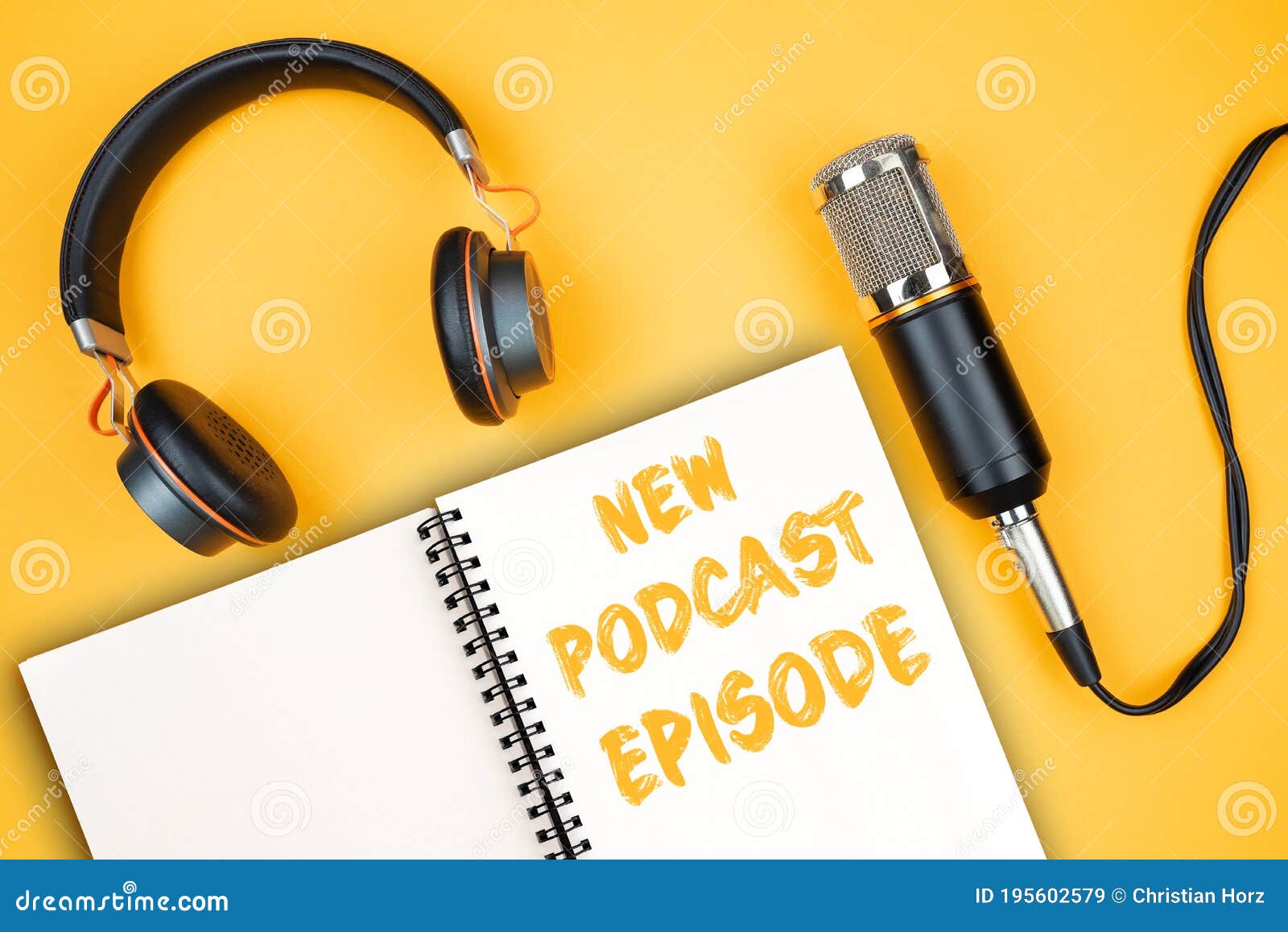 new podcast episode text on notepad next to headphones and recording microphone