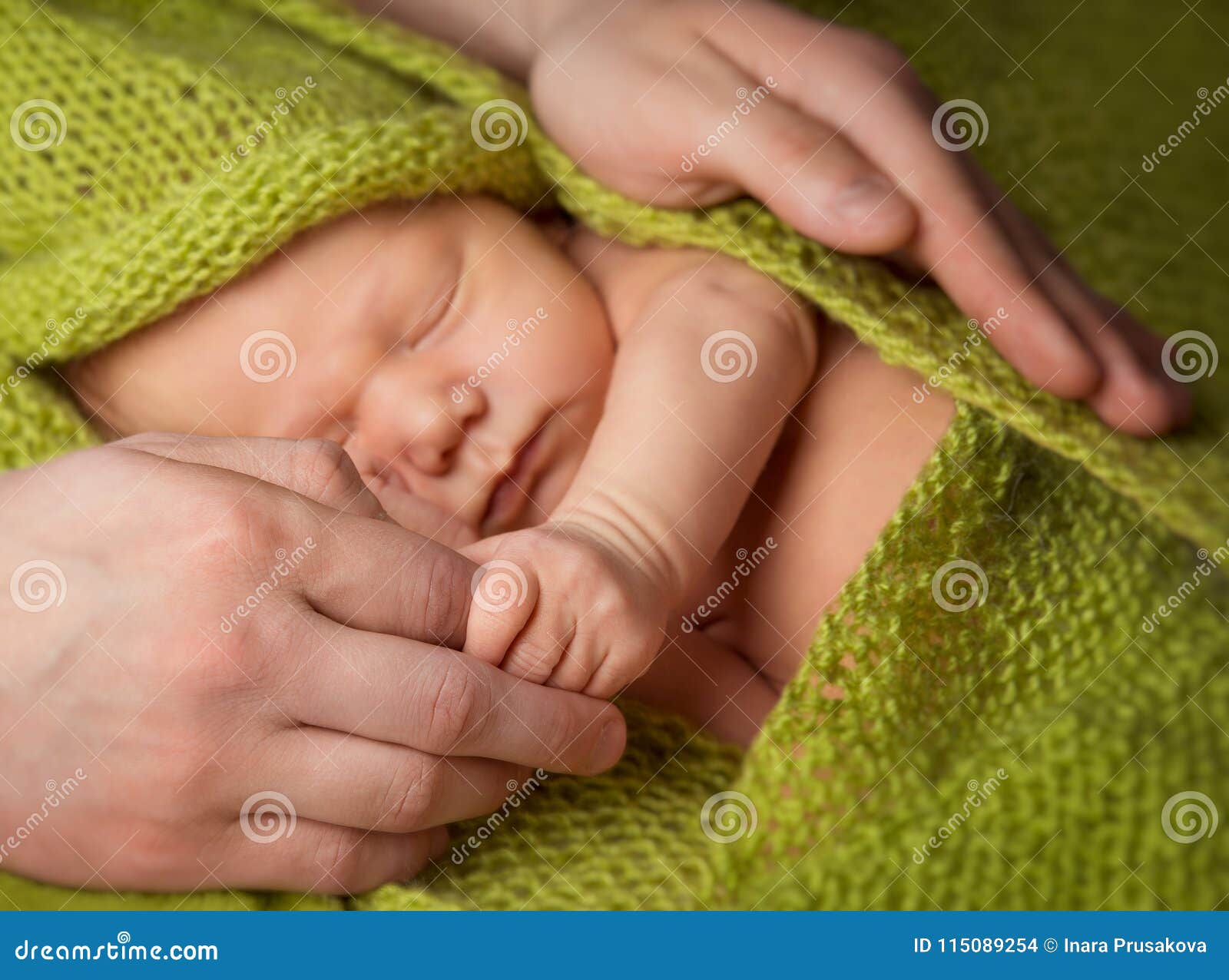 newborn baby sleeping in father hands, parent protecting new born child, one month child sleep under green woolen blanket