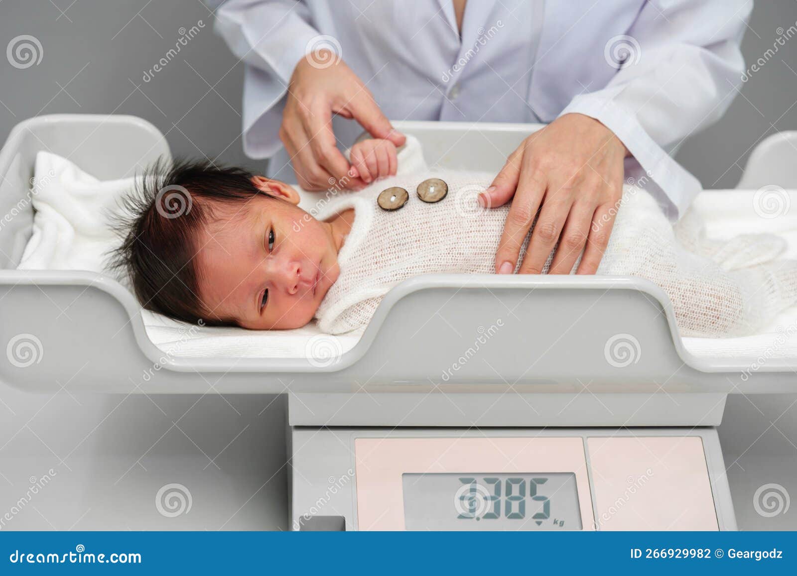 Newborn baby on weight scale in hospital Stock Photo