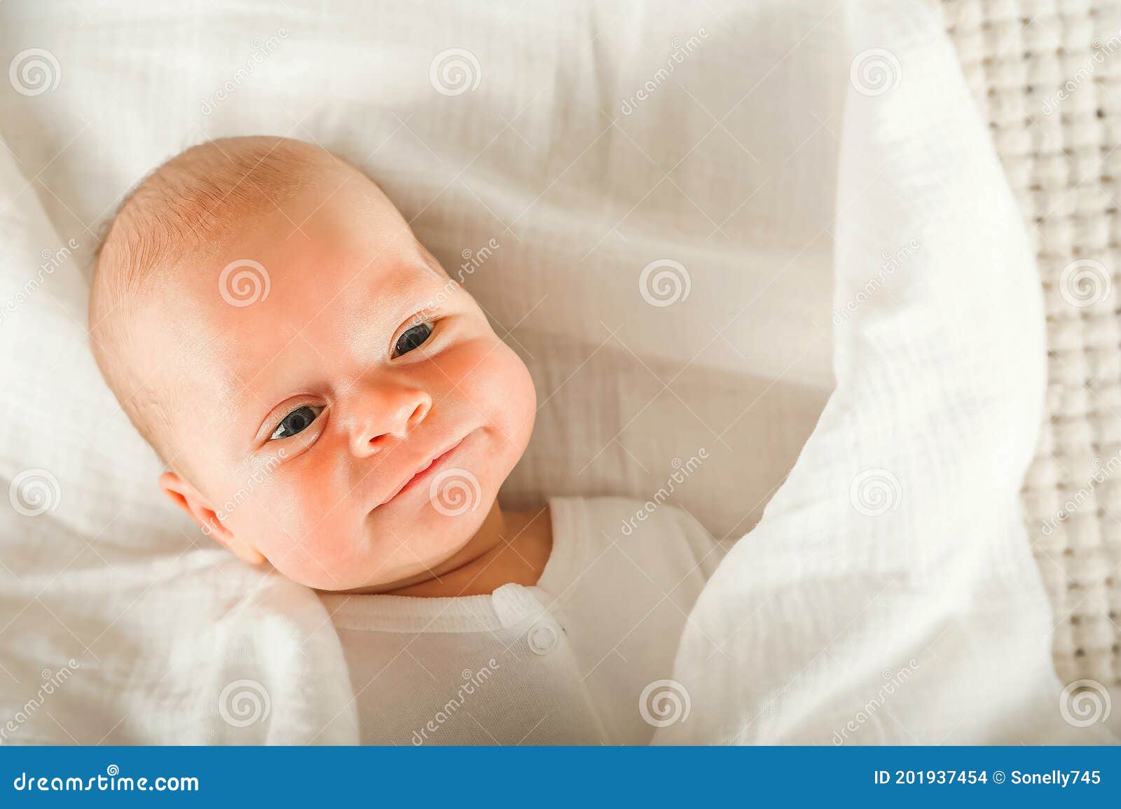 Newborn Baby in a White Diaper Close Up. Baby Swaddling in Muslin Diaper and Copy Space. Stock