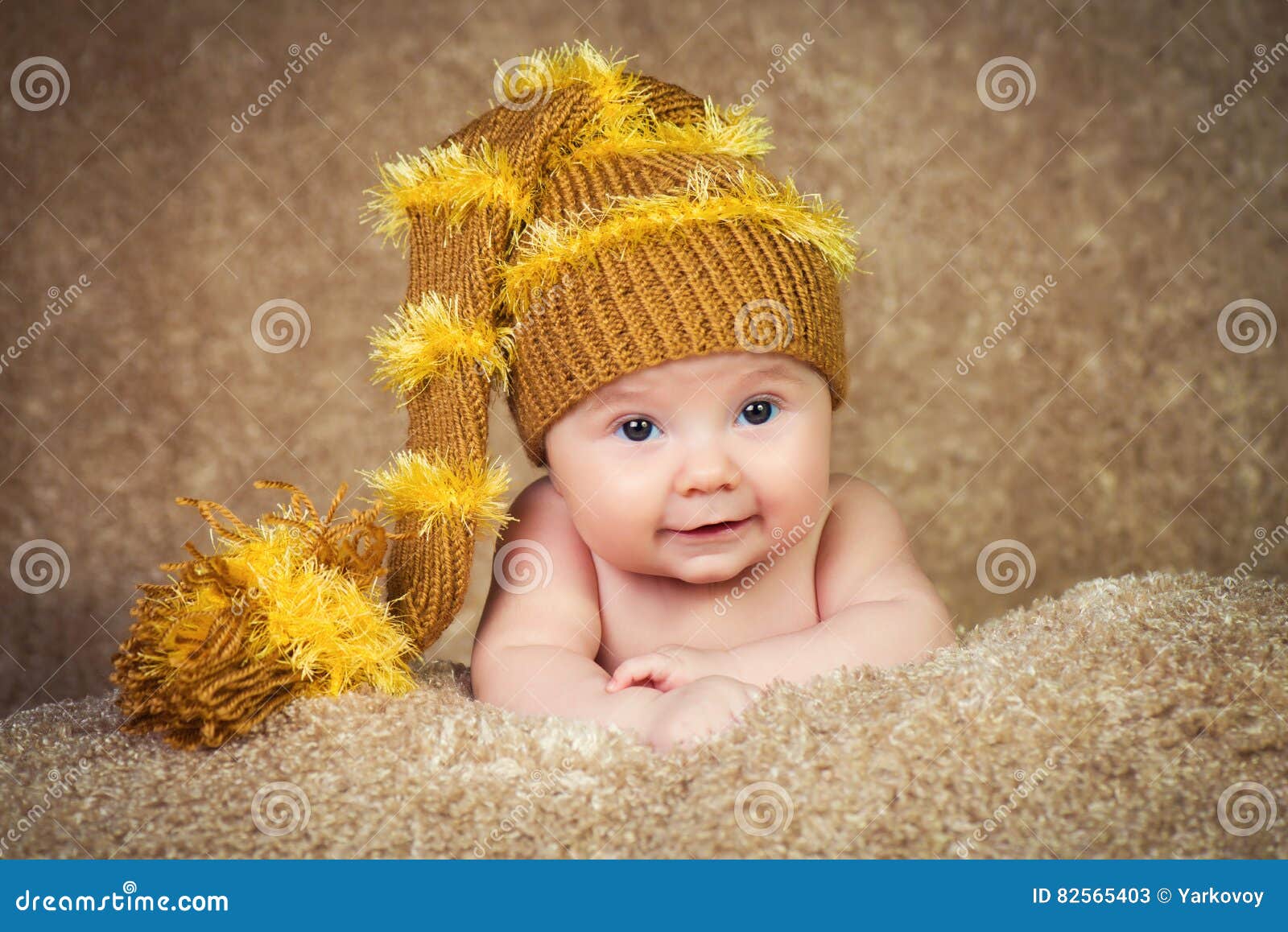 Newborn in Knitted Winter Hat on a Beige Background. Stock Image