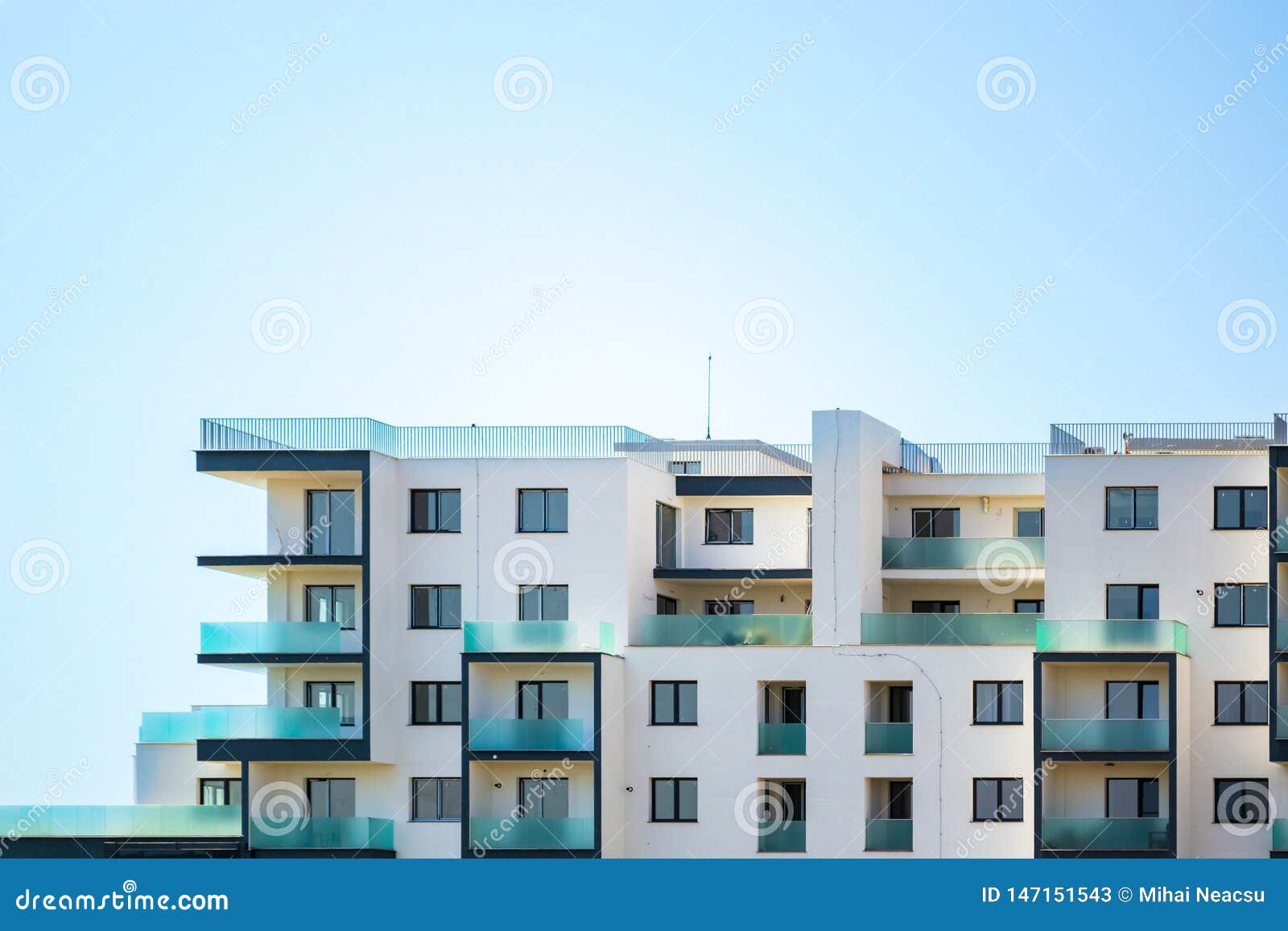 newly built apartments building on a bright blue sky, with space for text on top. upper part of a white building.