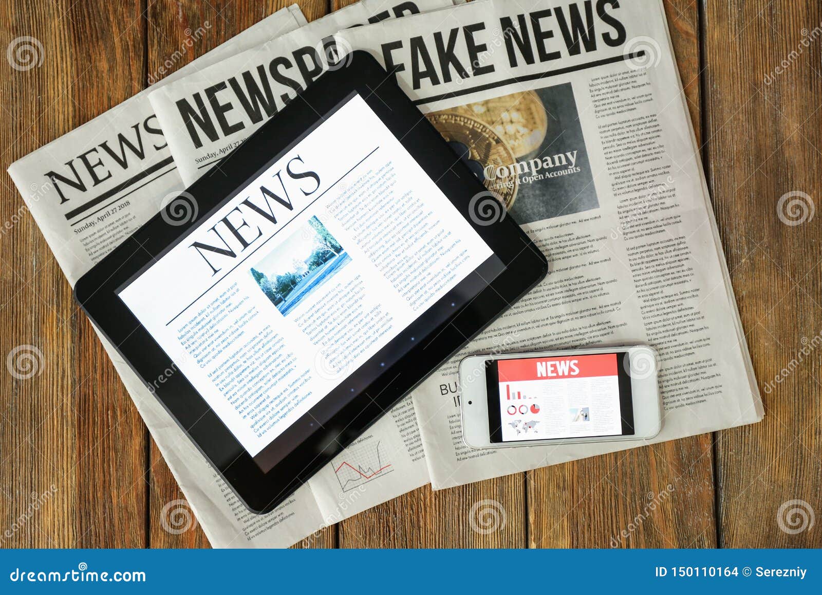 newspapers, tablet computer and phone with news on screen on wooden table