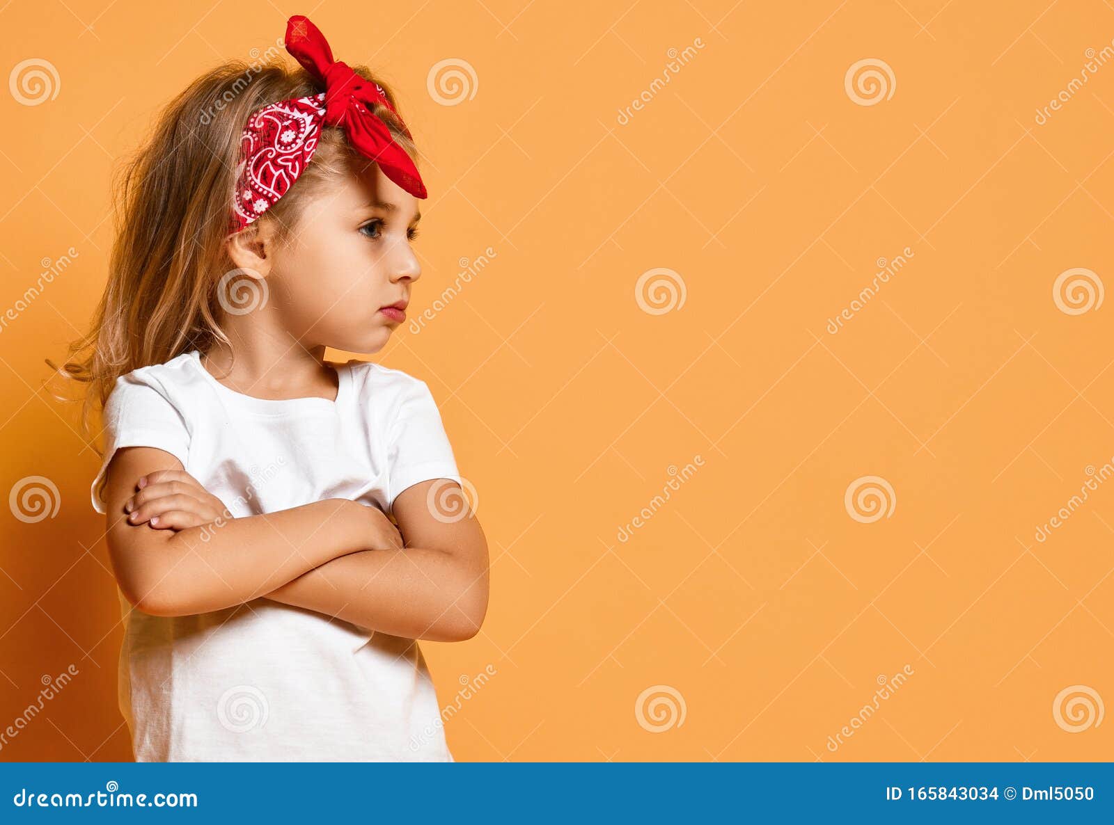 Niña feliz sonriente con las manos cruzadas en camiseta verde aislado sobre  fondo blanco.