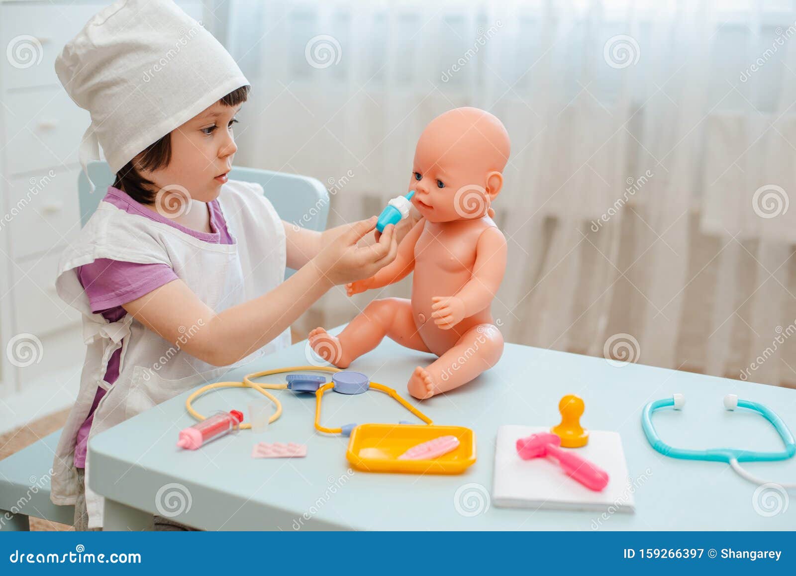 Niña de 3 años de edad preescolar jugando al doctor con muñeca el niño hace  un juguete de inyección