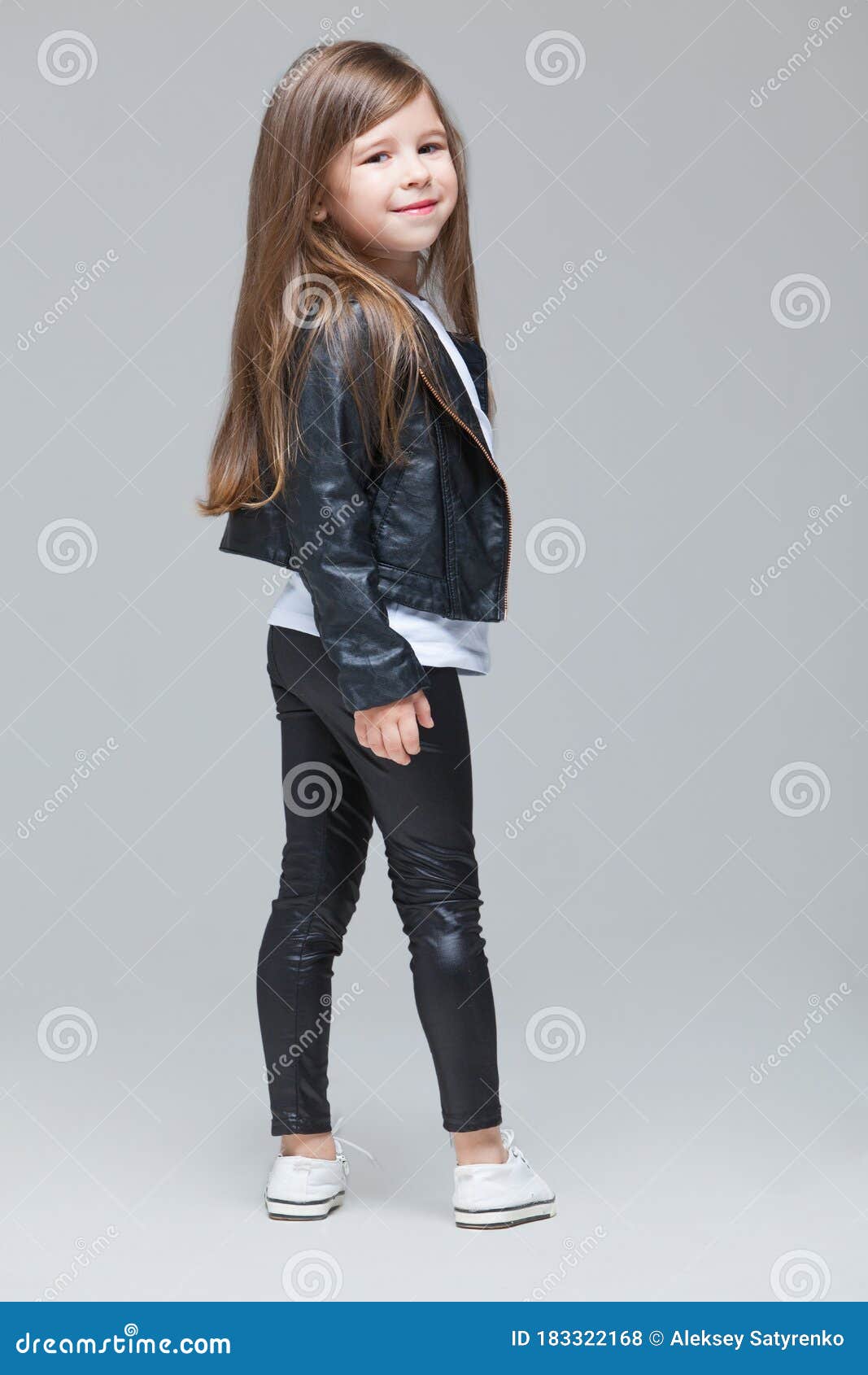 Niña De Pelo Largo Con Chaqueta De Cuero Negro Y Piernas De Pie En El Estudio De Fondo Gris Foto de archivo - de delgado, serio: 183322168