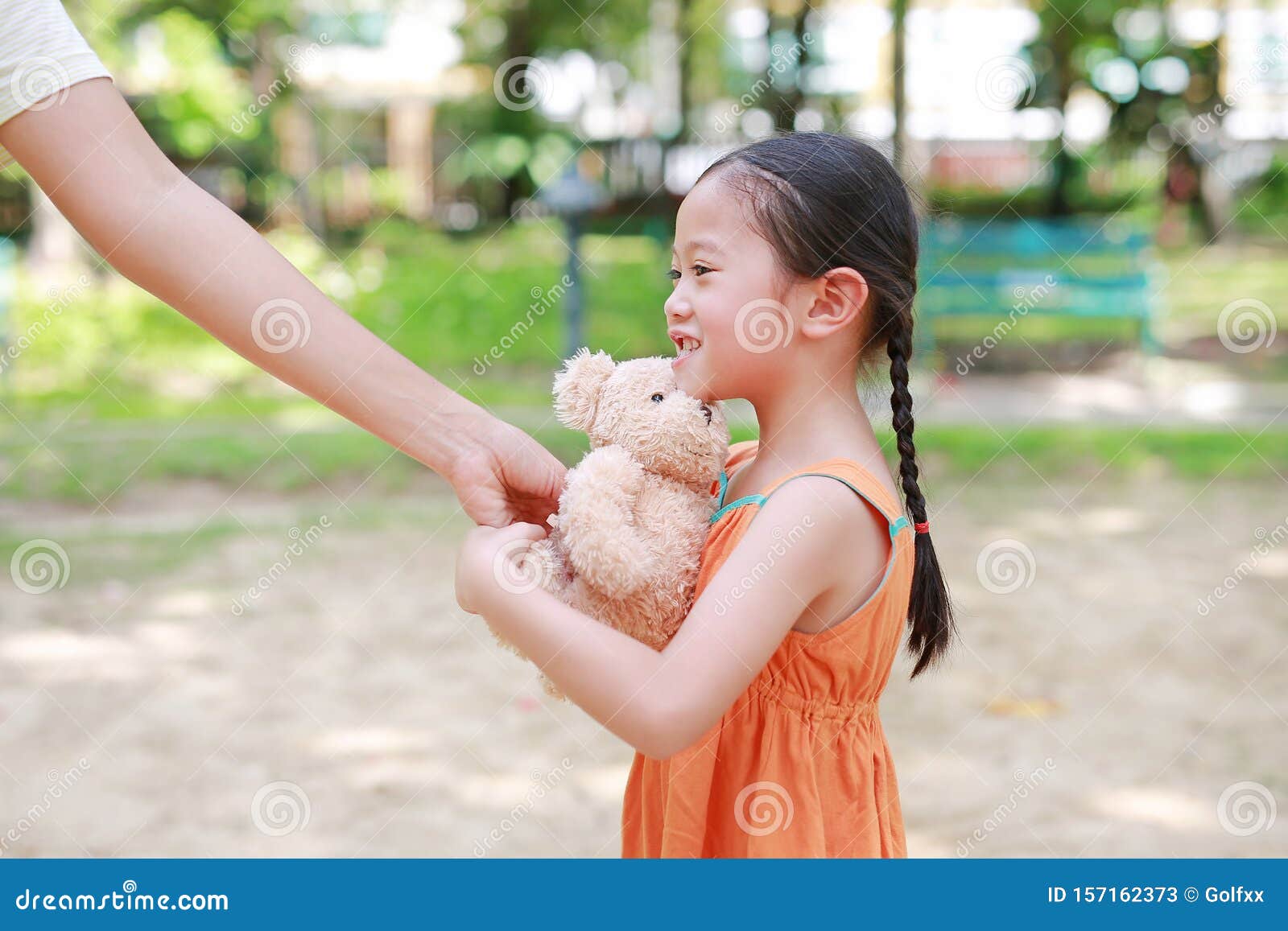 Niña Feliz Asiática Consigue Una Muñeca De Oso De Peluche De Su Madre En El Parque Al Aire Libre. Regalo Sorpresa De Mamá Por Imagen de archivo - Imagen de parque, regalo: