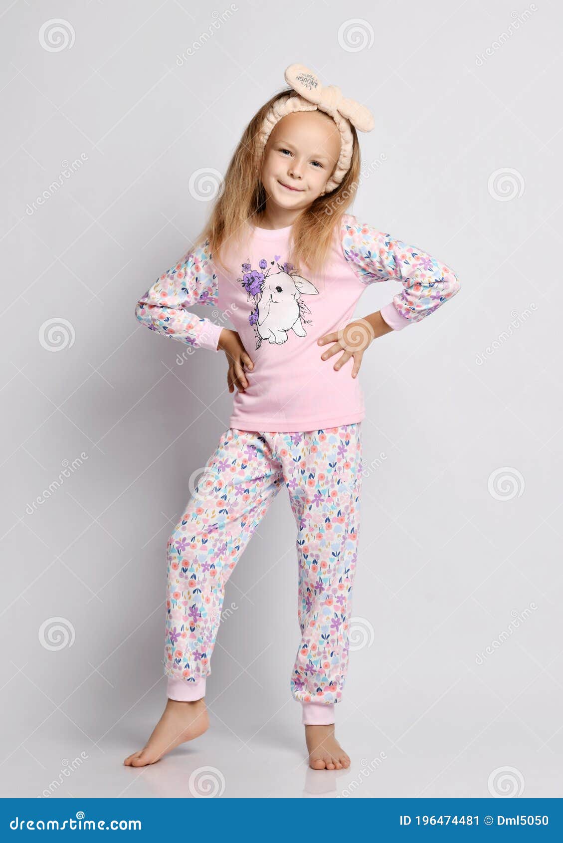 Niña Rubia Y Mona Sonriente Con Camisa Elegante Y Pijama Pantalones Con Estampado De Flores Se Pone De La Mano En La Cintura Imagen de archivo - de descalzo, rosa: