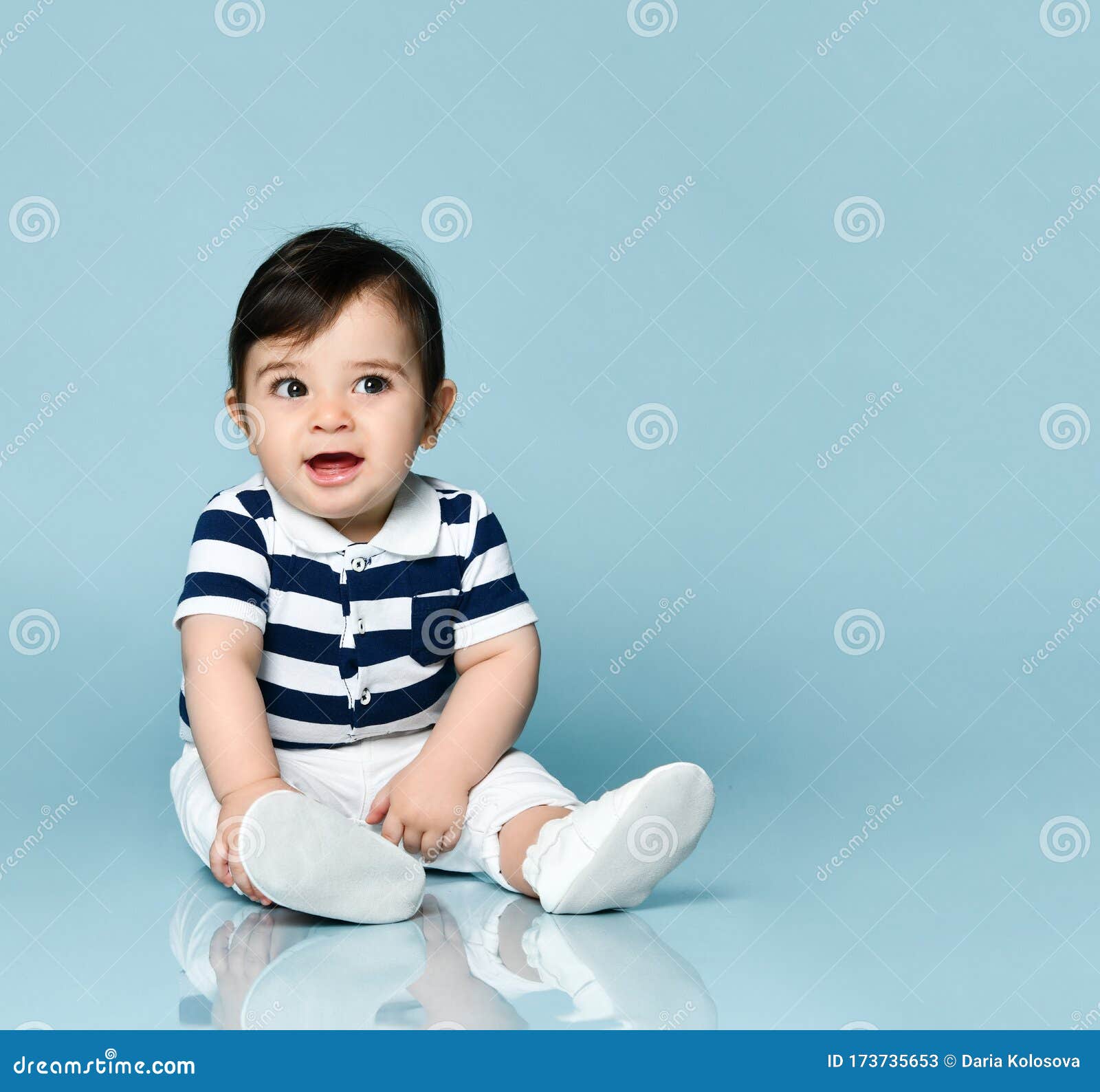 Niño Con Camiseta a Rayas, Pantalones Blancos Y Botellas Está Sonriendo, Sentado El Suelo Sobre Azul De Estudio Cerrar Imagen de archivo - Imagen de anuncio: 173735653