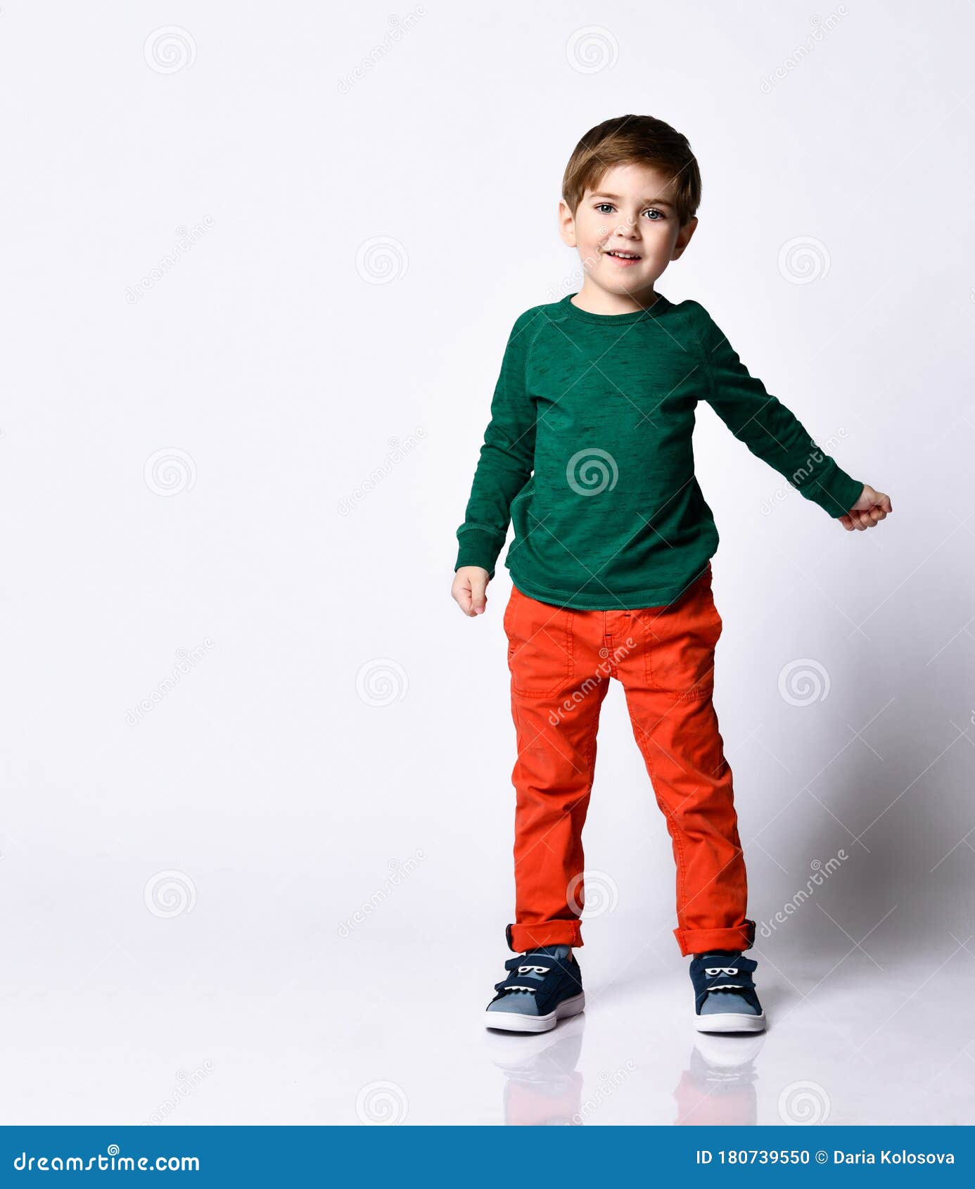 Niño Pequeño Con Pantalones De Naranja Y Zapatillas De Tenis Azules. él Está Sonriendo Mientras Posa Aislado En El Fondo Blanco Foto de archivo - Imagen de manera, feliz: