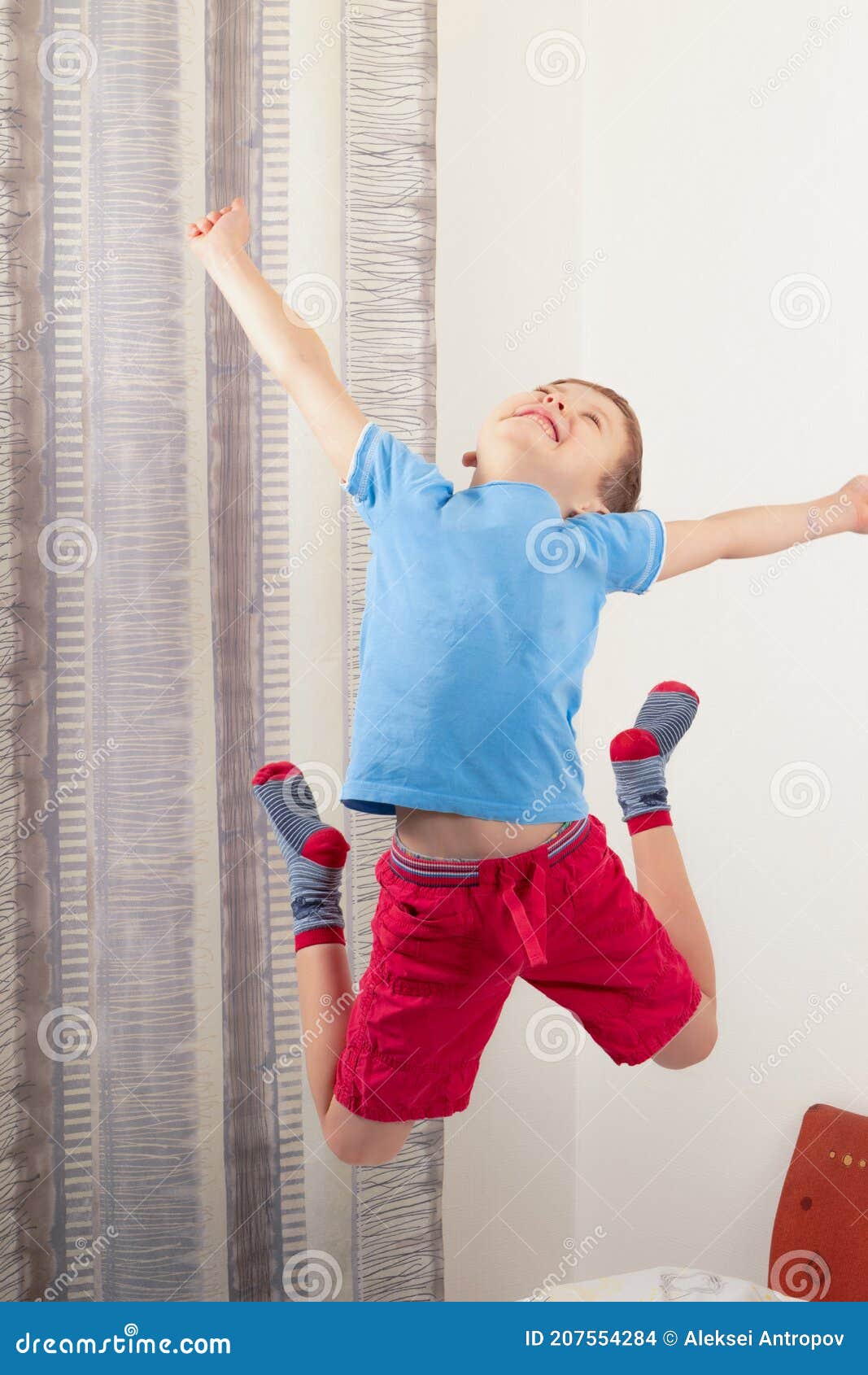 Pequeño Con Una Camiseta Azul Y Pantalones Cortos Rojos Saltando Alto En La Cama Foto de archivo - Imagen de emocional, casero: 207554284
