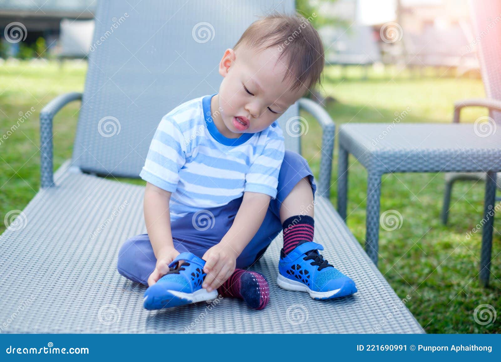 Niño Pequeño Y Lindo Asiático Sentado Y Concentrado En Ponerse Sus Propios Azules Zapatillas De Tenis Imagen de archivo Imagen de confianza,