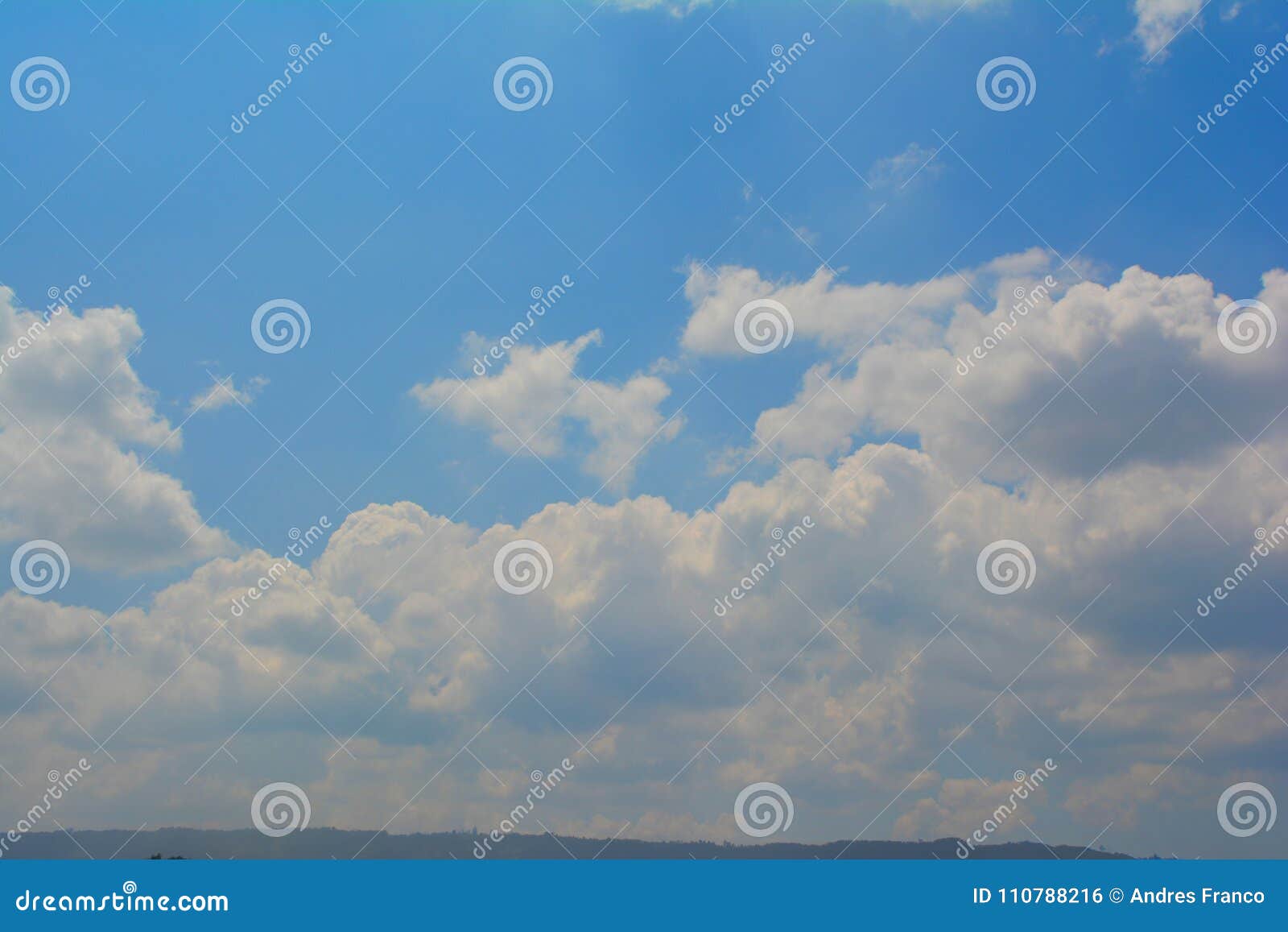 nice blue sky on a sunny day with a wall of clouds and a mountain on the bottom