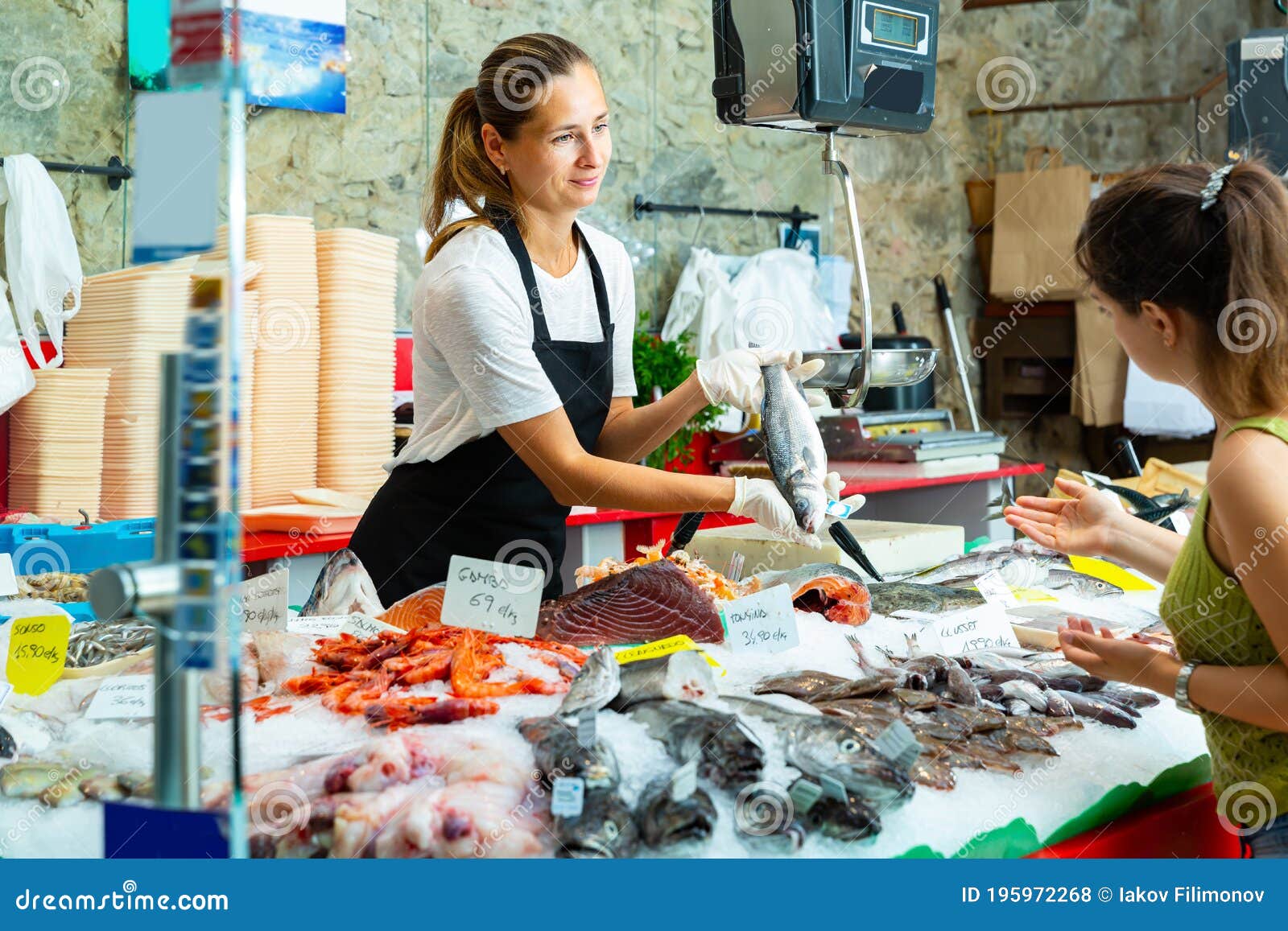 Nice Worker Offering Fresh Sea Bass To Woman Stock Photo - Image