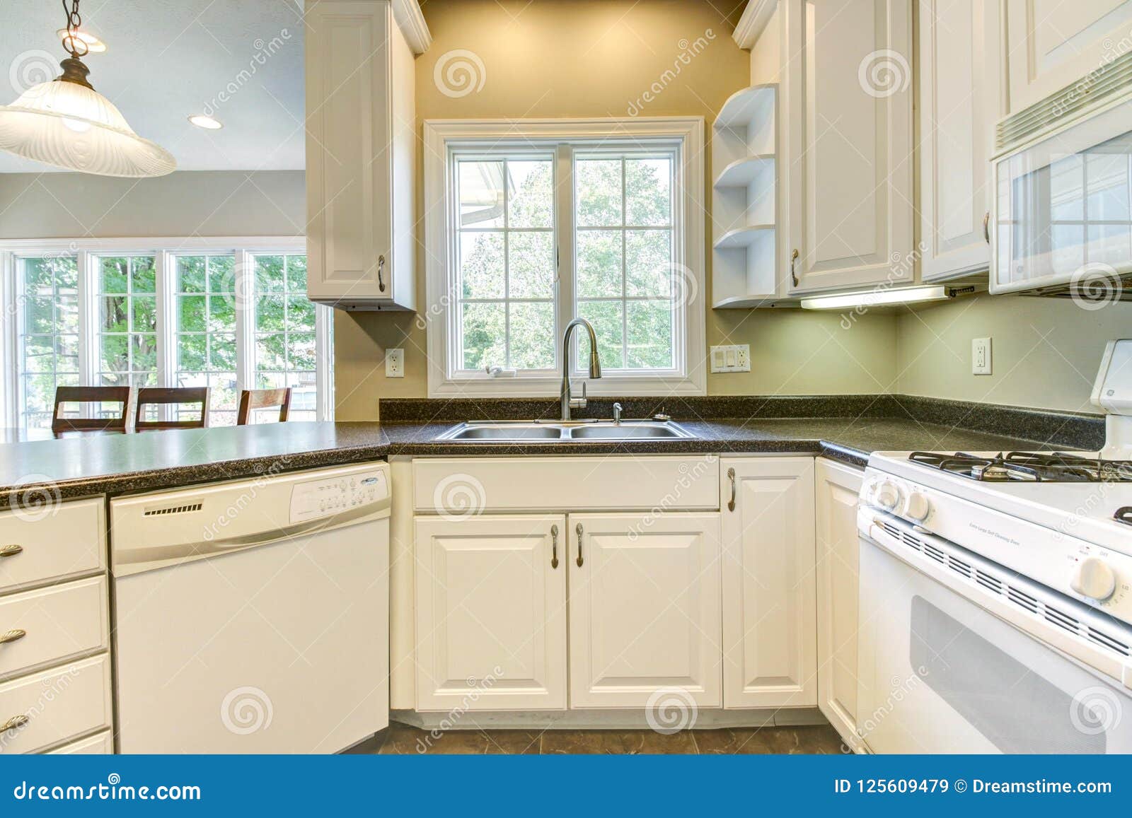 Nice Kitchen With White Cabinets And Black Countertops Stock