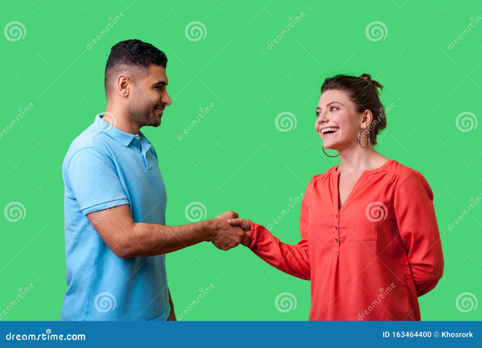 nice to meet you! portrait of happy young couple in casual wear shaking hands.  on green background