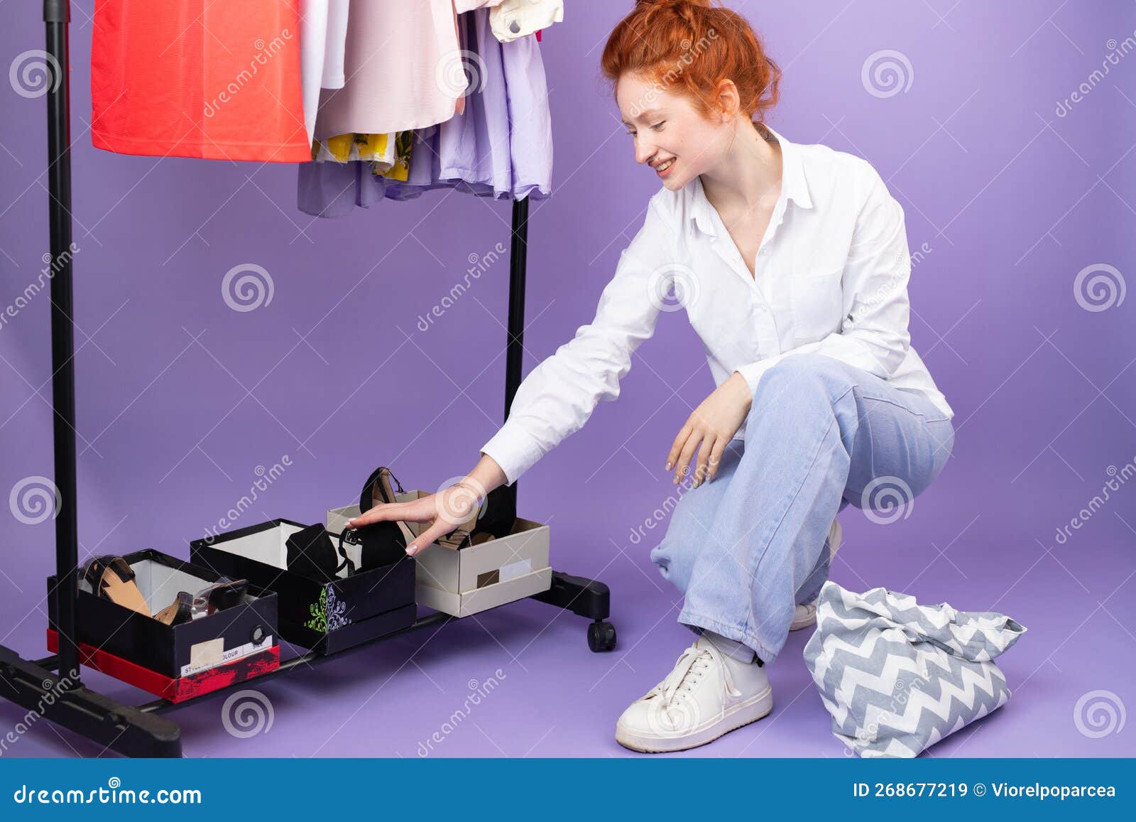 nice young caucasian woman do shooping in clothes and shoes store on purple bacckgroung at studio - consumism and