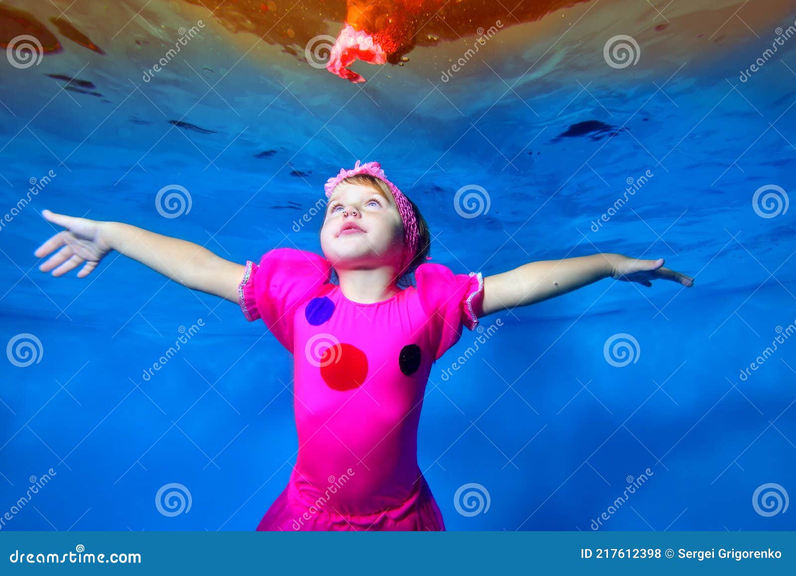 Niedliche Kleine Mädchen Schwimmt Und Posiert Unter Wasser Im Pool In Einem Roten Kleid Arme
