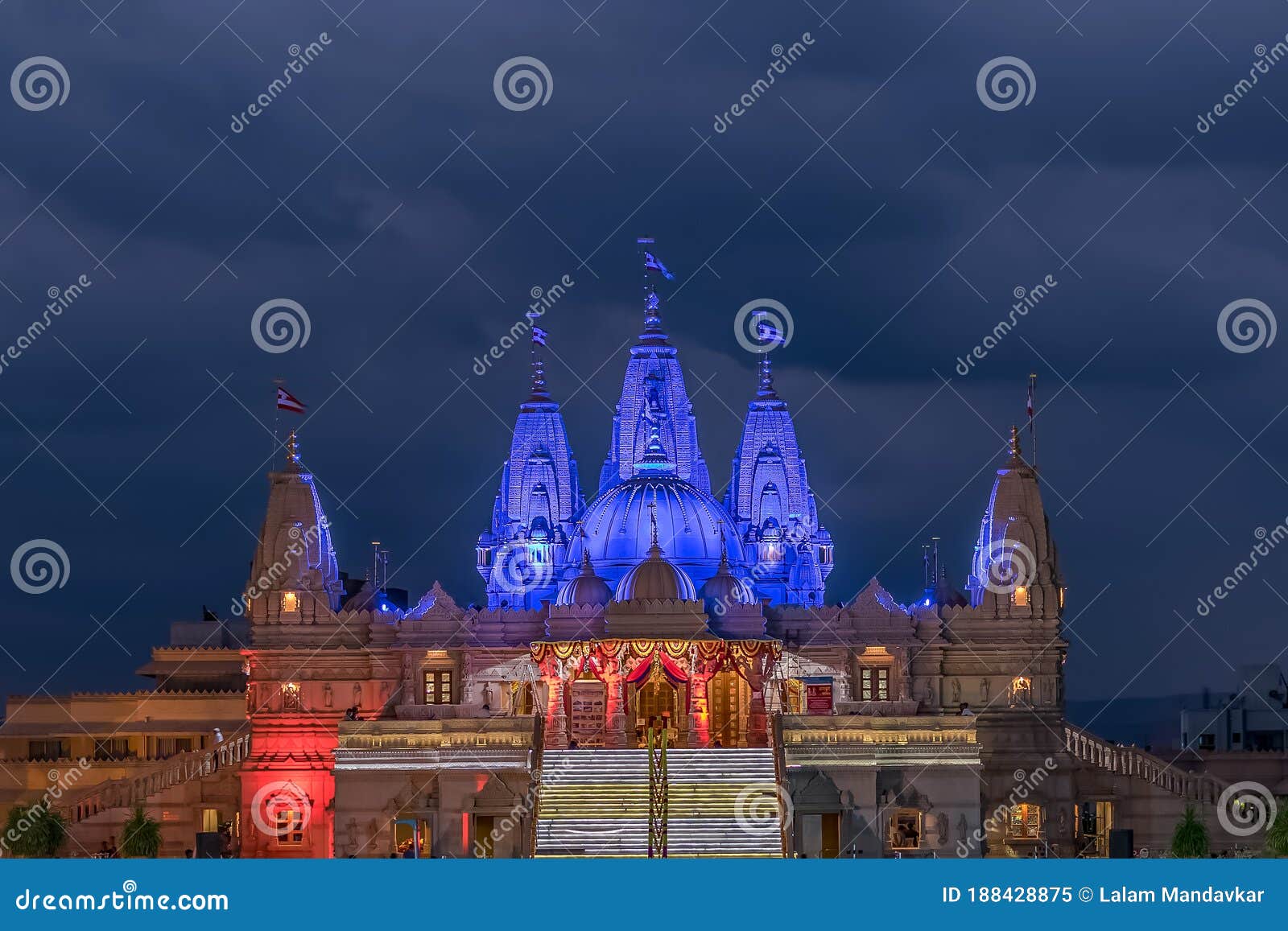 night lighted image of shree swaminarayan temple with monsoon clouds background., ambe gaon, pune .