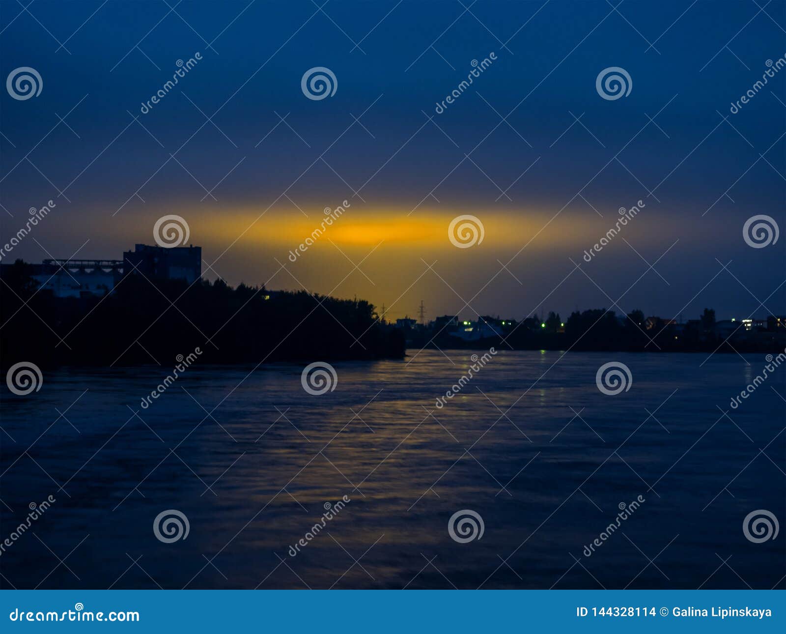 Night Sky with Reflection of the Yellow Lights of the City Stock Photo