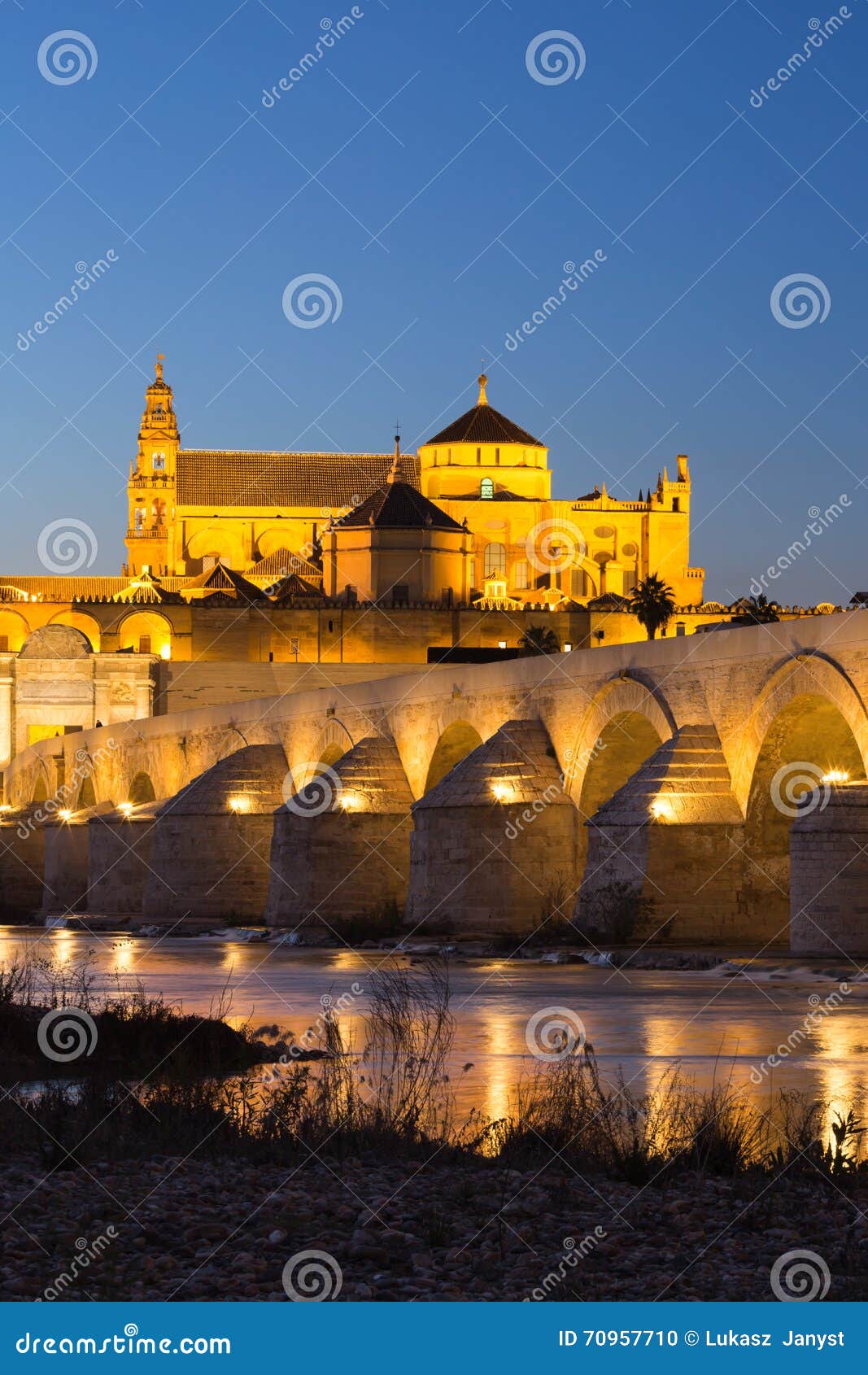 night view of mezquita-catedral and puente romano - mosque-cathedral and the roman bridge in cordoba, andalusia, spain