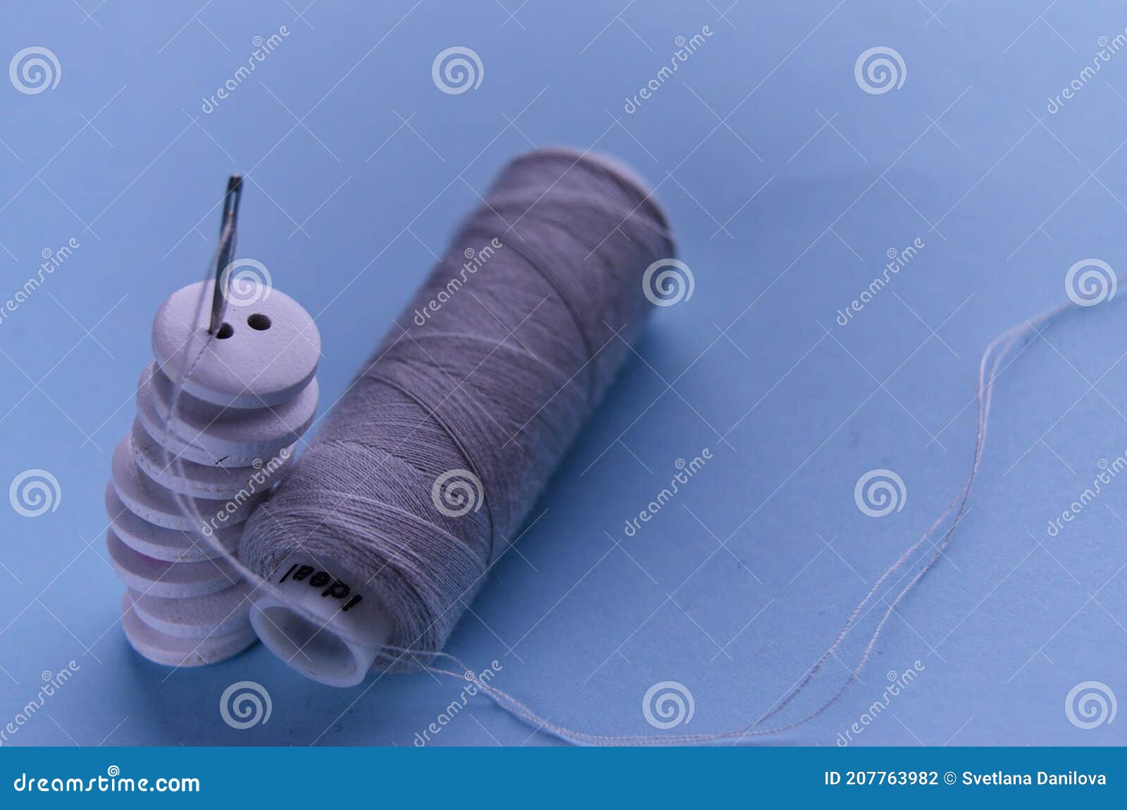 Nine White Wooden Buttons Stacked with a Needle and Gray Threads on a ...