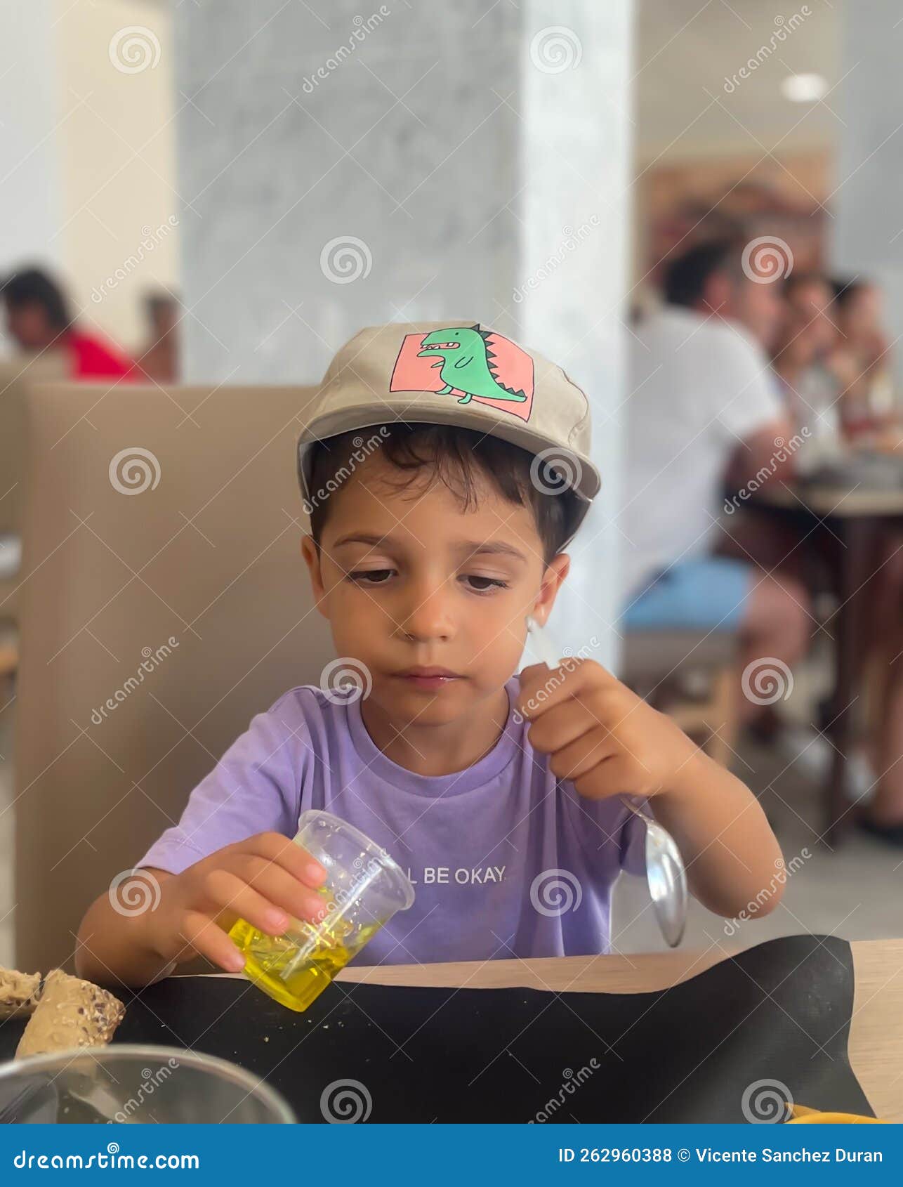 niÃÂ±o saborea una vaso de gelatina amarilla sentado en un restaurante