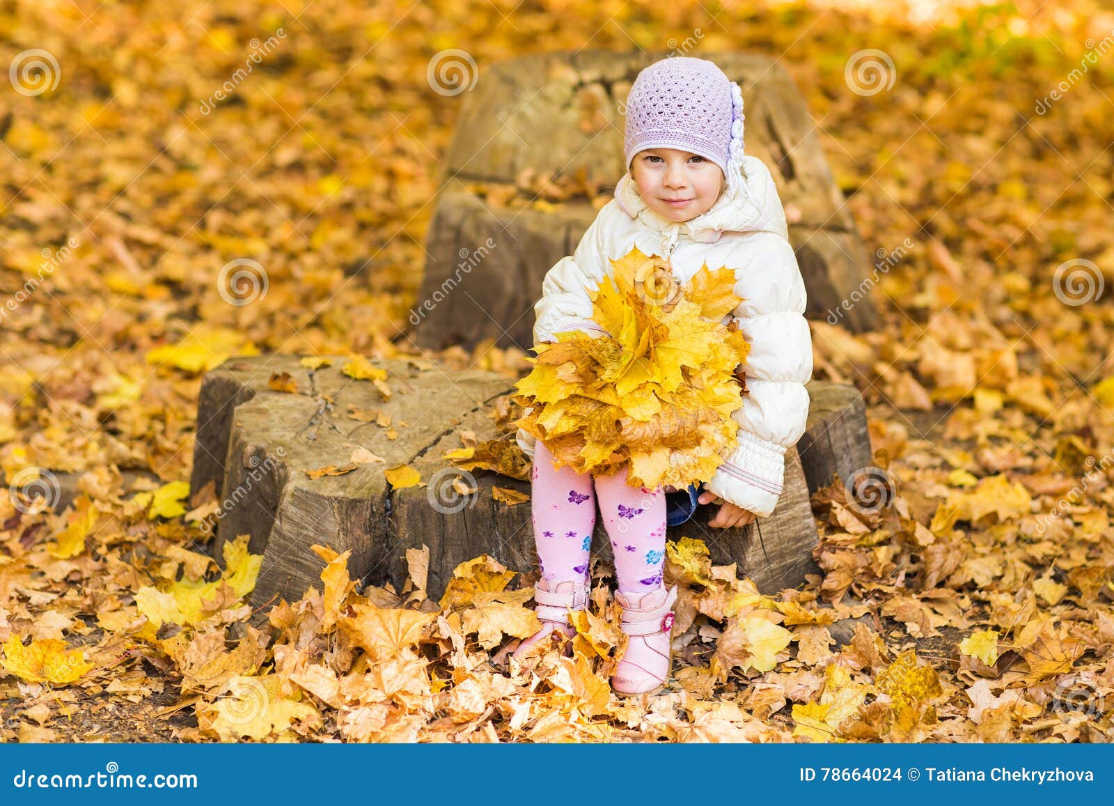 Niña adorable con las hojas de otoño en el parque de la belleza