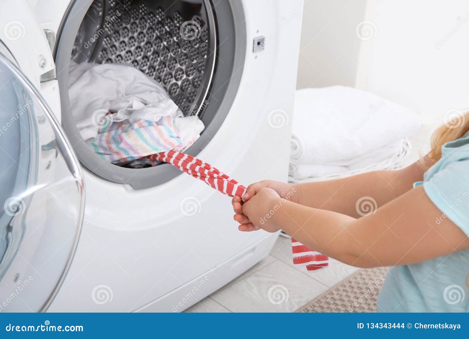 Niña Adorable Que Saca La Ropa De La Lavadora, Primer Foto de archivo