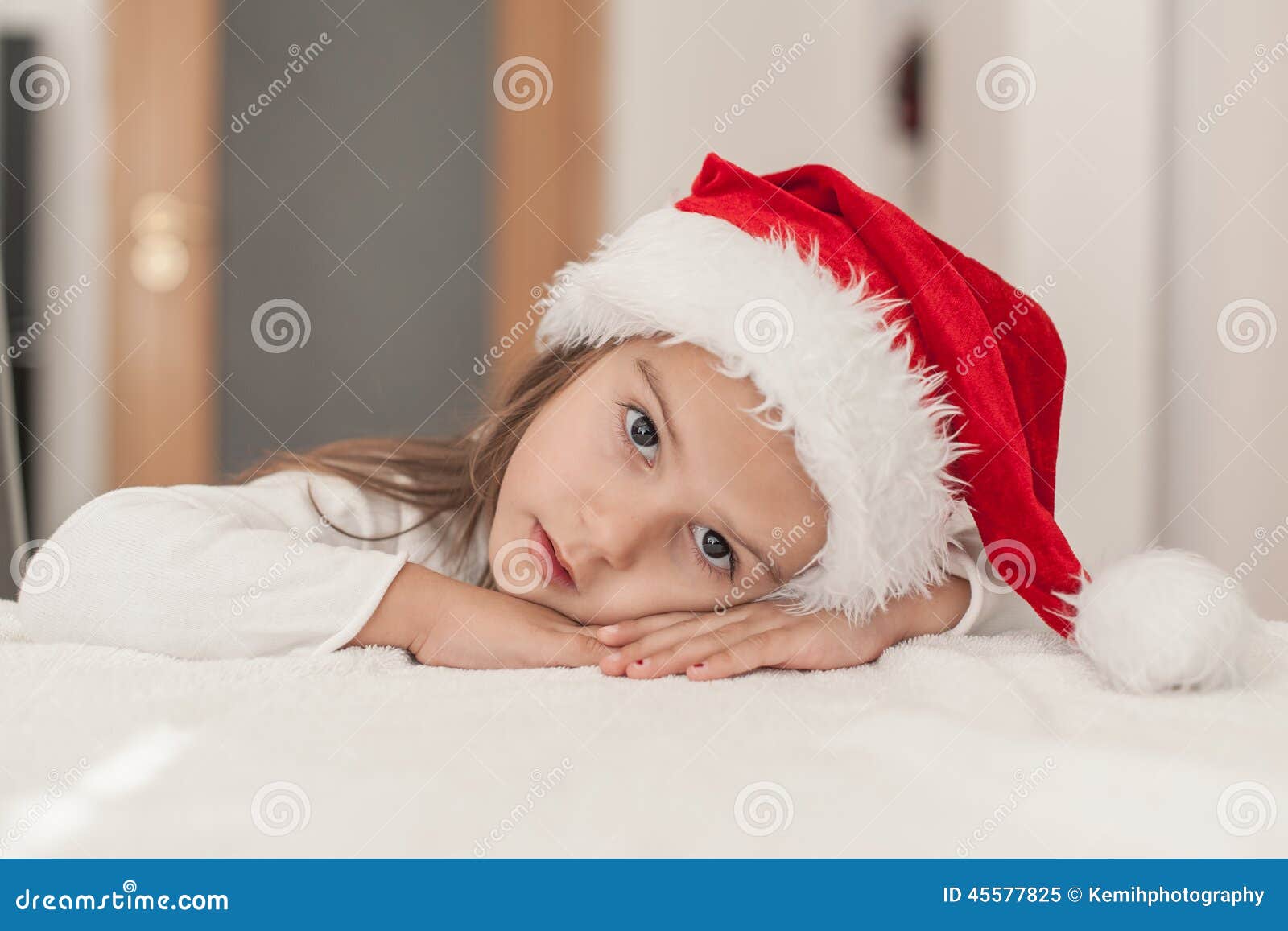 Niña con el sombrero para Papá Noel que espera de la Navidad en casa en