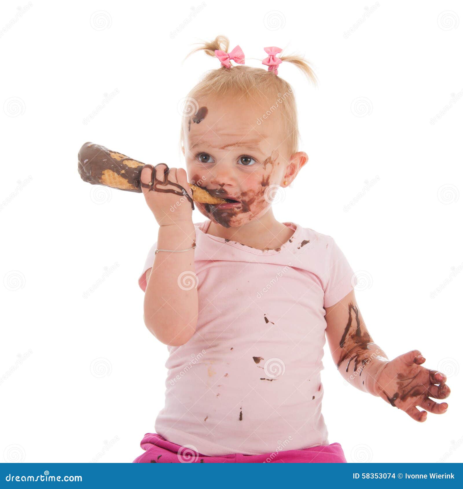 Niña pequeña que come el helado. Niña pequeña del retrato que come el helado de chocolate aislado sobre el fondo blanco