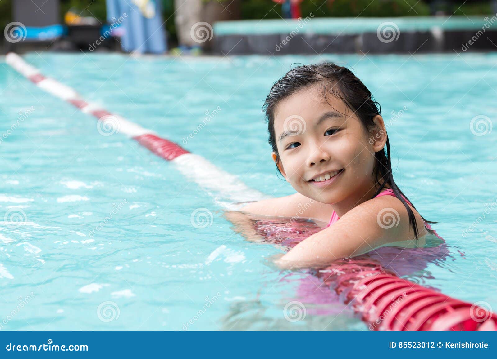 Niño asiático en la piscina. Pequeña muchacha asiática en la piscina soleada