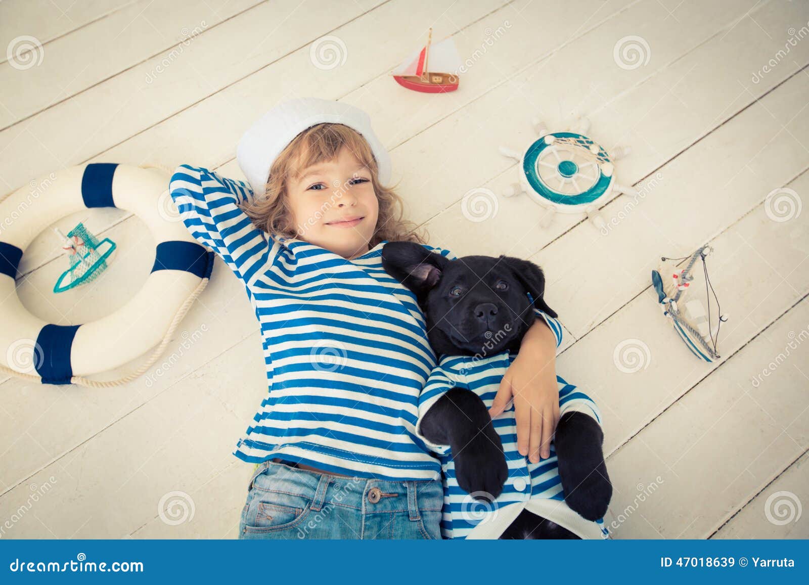 Niño y perro. Niño feliz vestido en marinero Niño que juega con el perro en casa Concepto del viaje y de la aventura