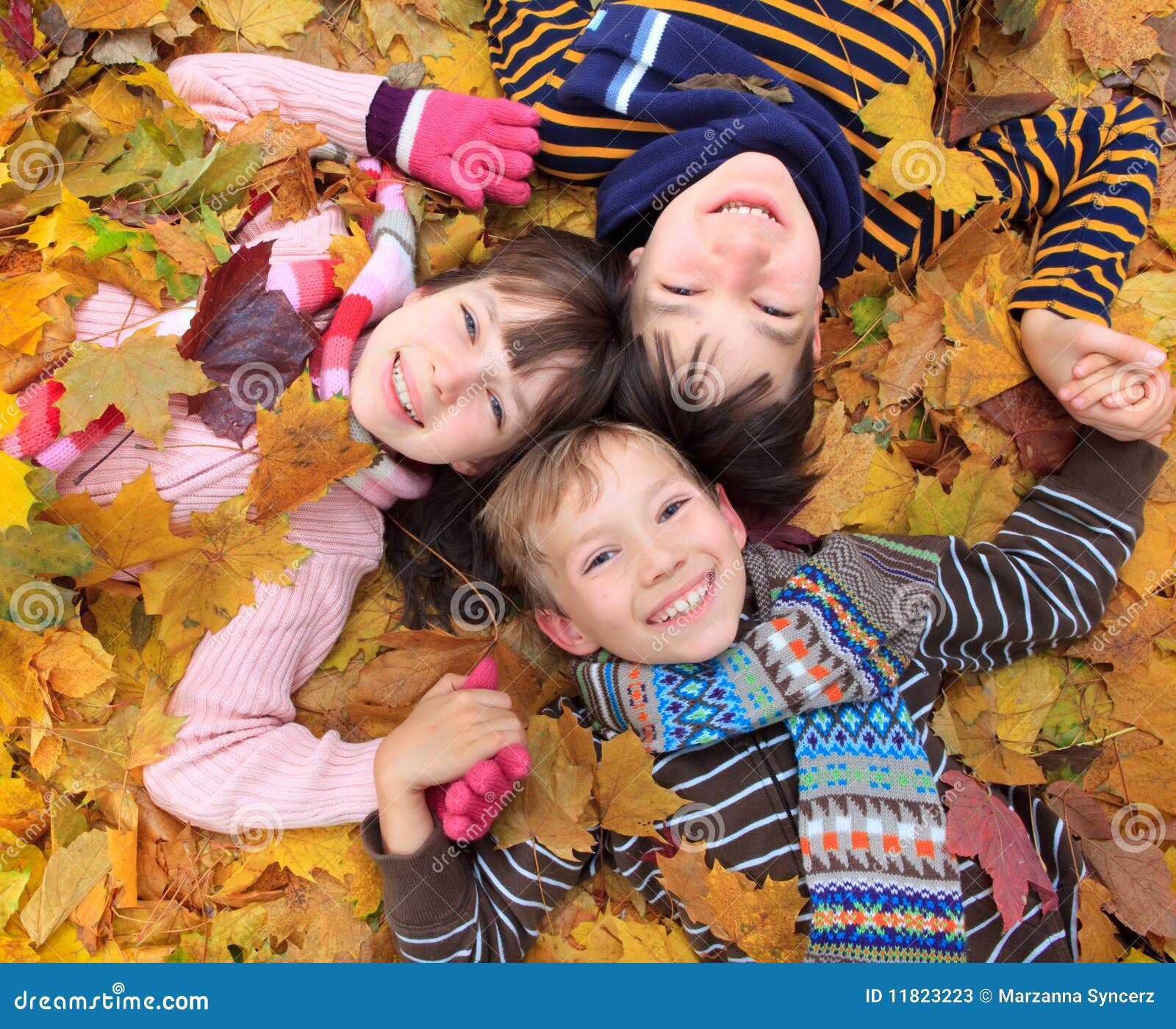 Niños en las hojas de otoño. Tres hermanos que ponen en las hojas de otoño.