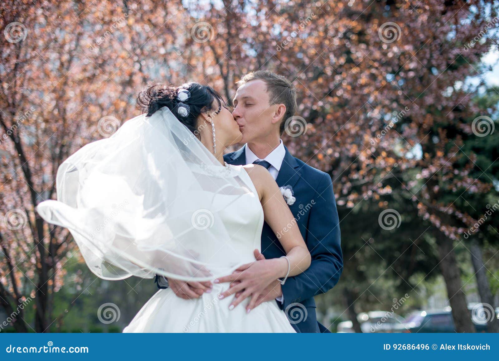 Noivos no dia do casamento que andam fora na natureza da mola Pares nupciais, mulher feliz do recém-casado e homem abraçando em p. Noivos no dia do casamento que andam fora na natureza da mola Pares nupciais, mulheres felizes do recém-casado e homens abraçando no parque verde Pares loving do casamento exteriores Noiva e noivo