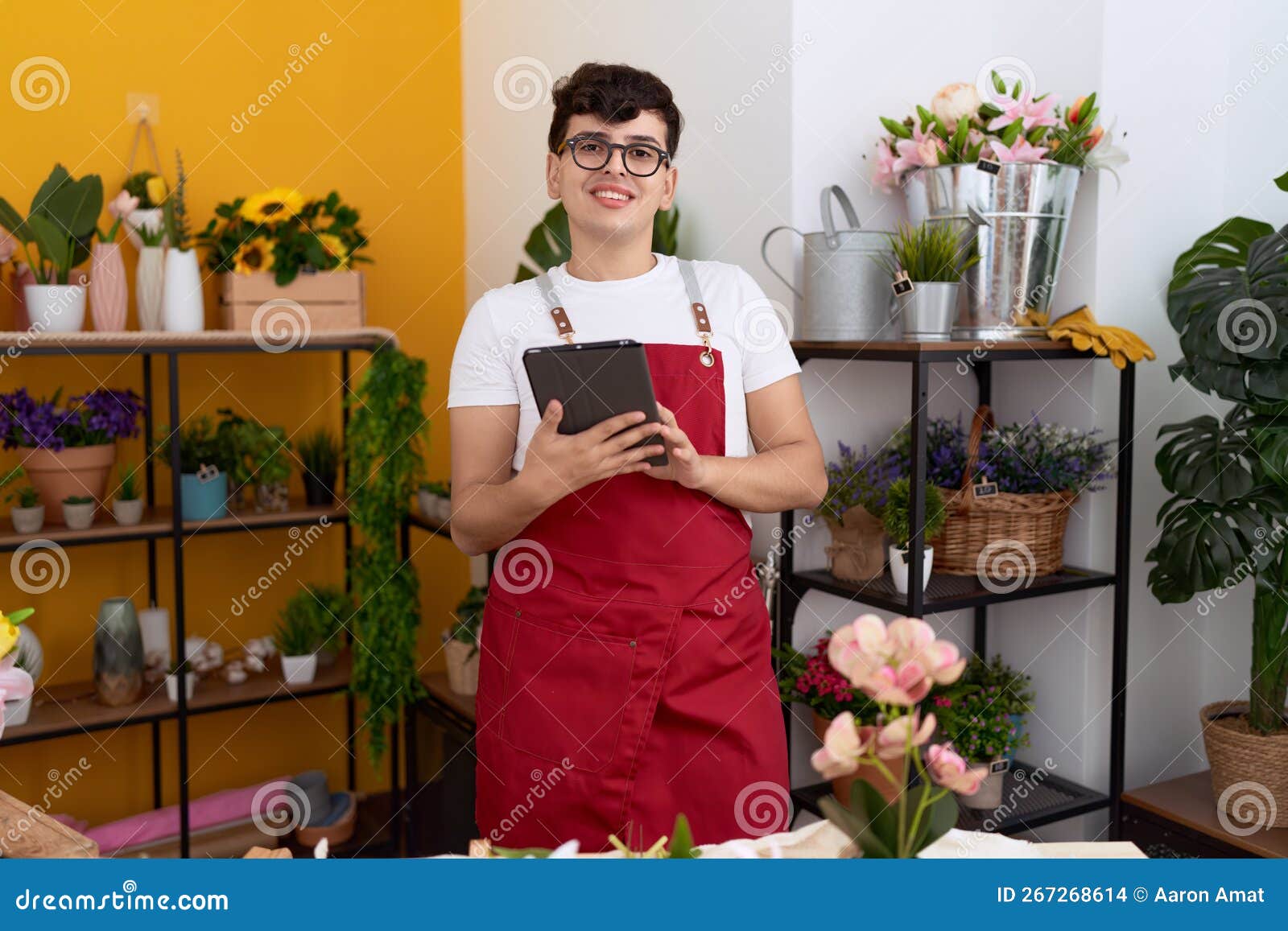 Non Binary Man Florist Smiling Confident Using Touchpad at Flower Shop