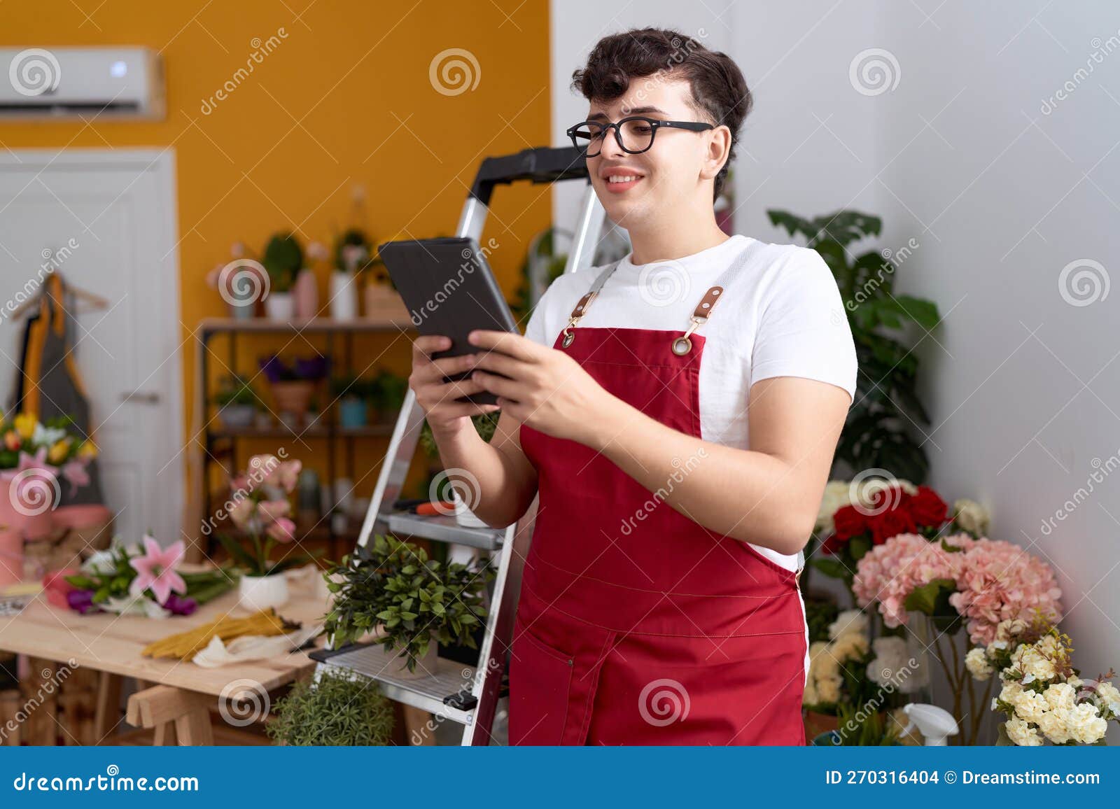 Non Binary Man Florist Smiling Confident Using Touchpad at Flower Shop