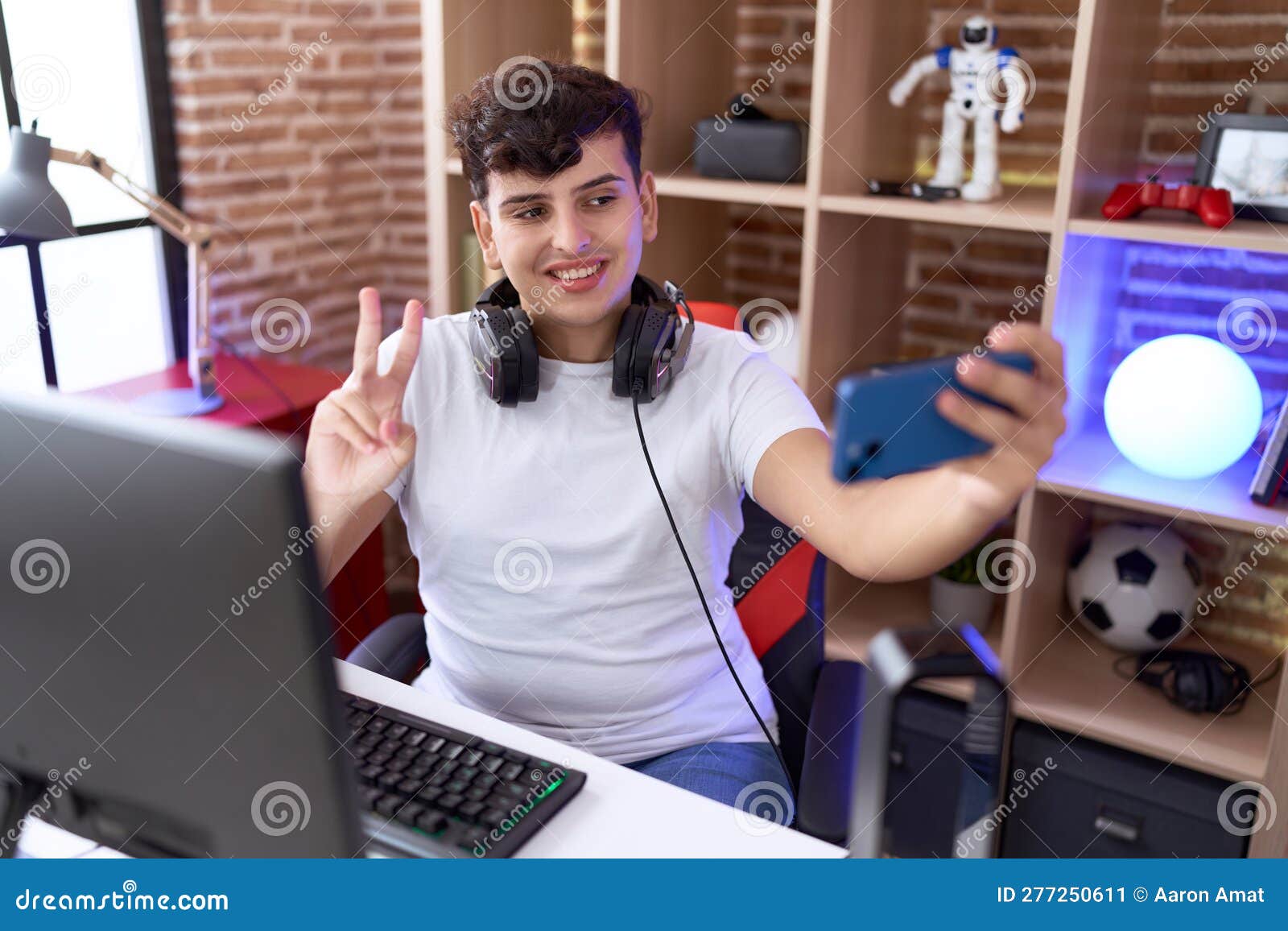 Non Binary Man Streamer Smiling Confident Make Selfie By Smartphone At Gaming Room Stock Image