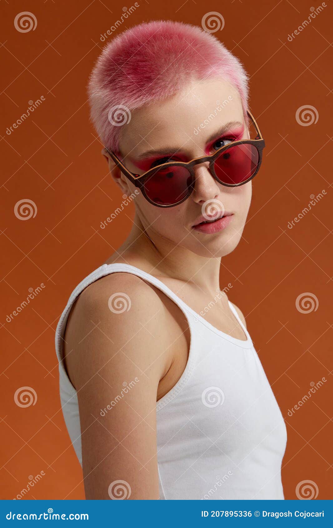 nonconformist girl with pink short hairs with red sunglasses, over brown background
