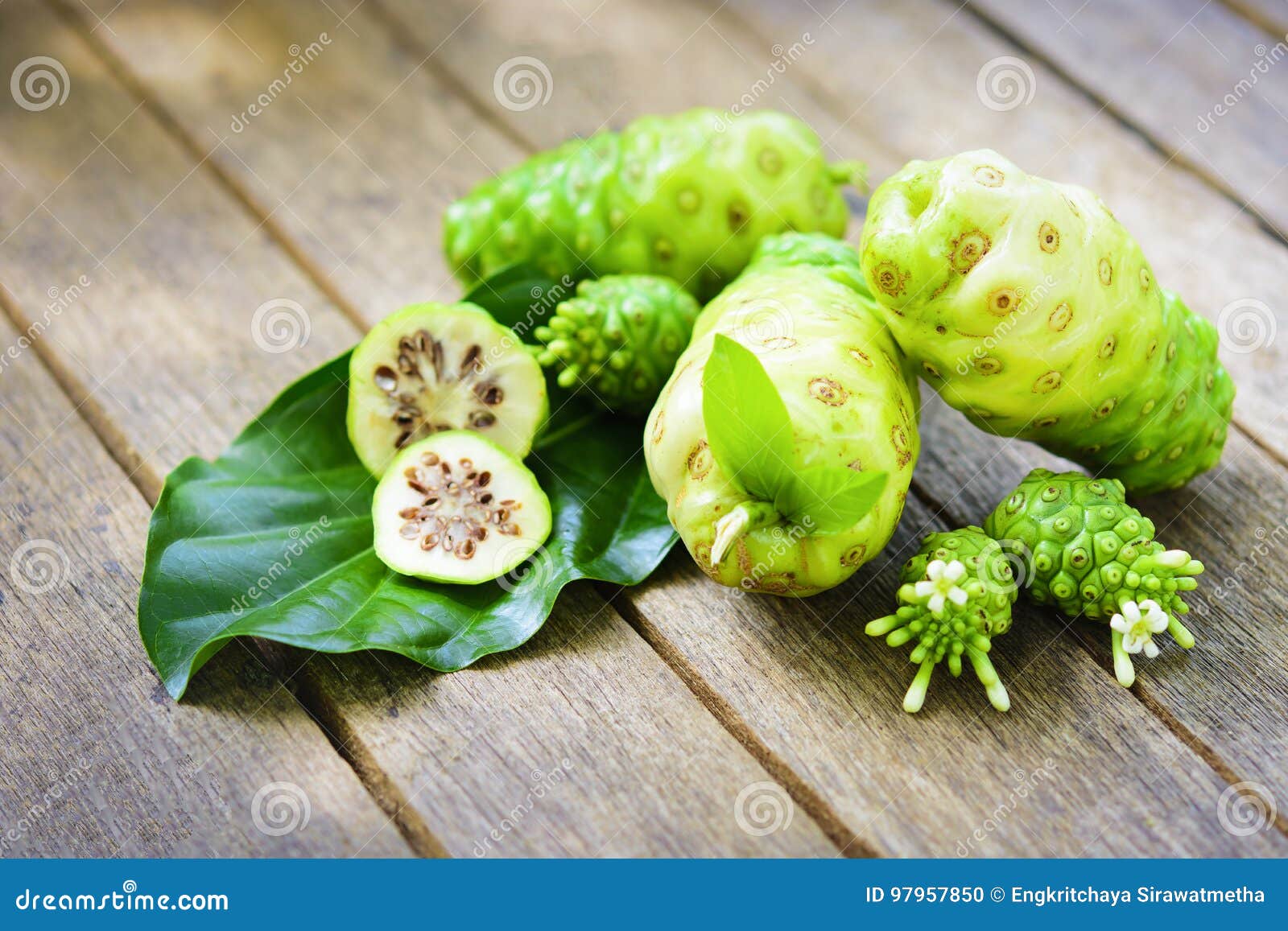Noni Fruit with Noni Slice and Blossom on Old Wooden Table. Stock Photo