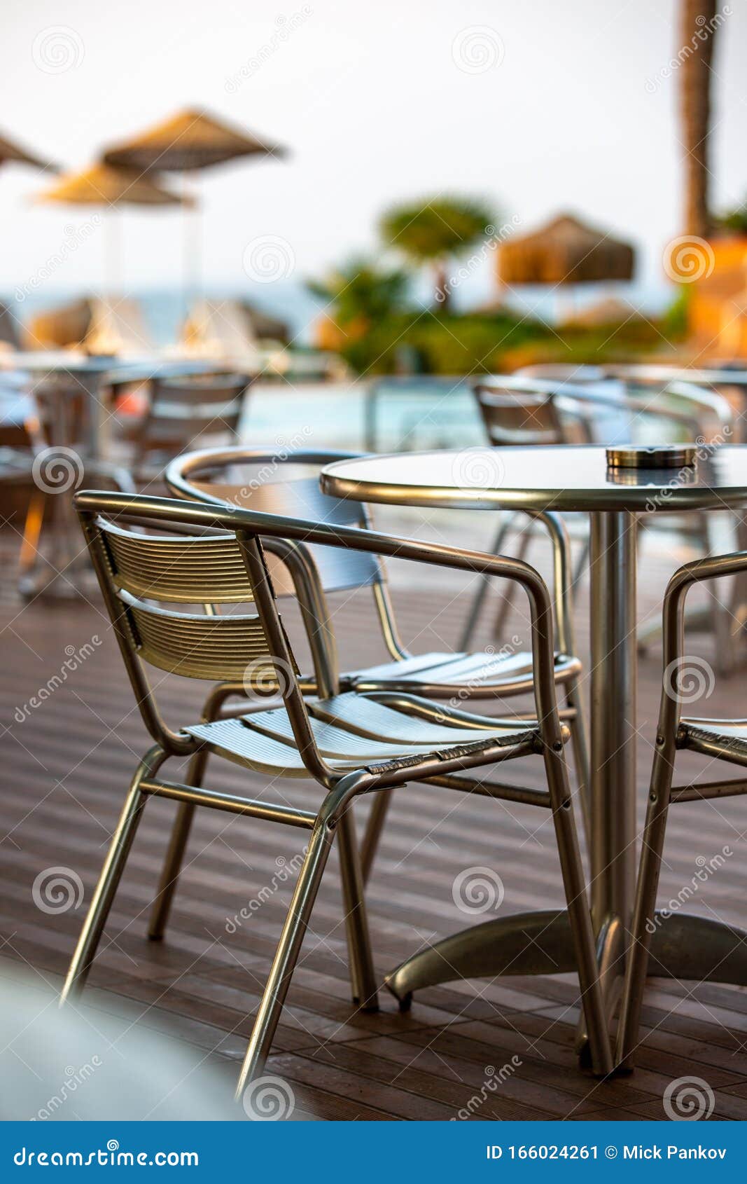 nook of street cafee with several metal chairs and tables near sea.