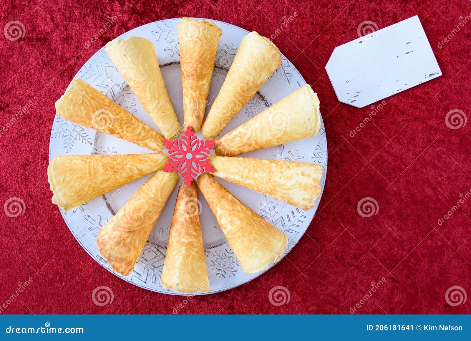 norwegian krumkake cookies on a white snowflake platter on a rich red background