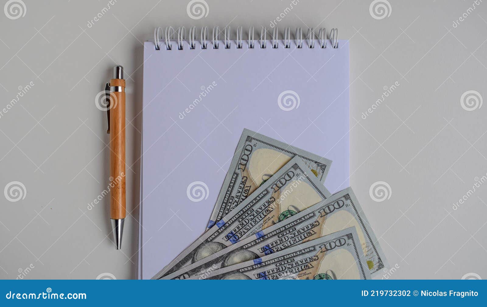 notebook for notes with hundred dollar bills and pen