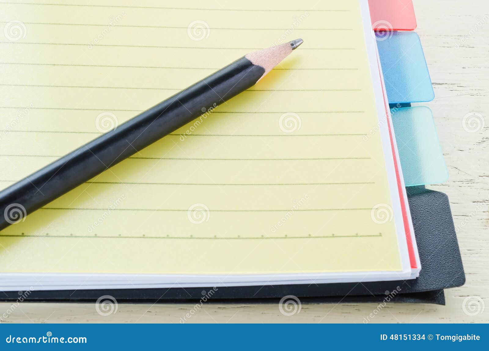 Notebook and pencil. Notebook s yellow bookmark and pencil on wooden table